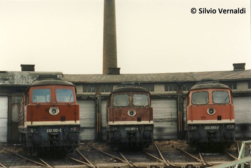 3 Ludmillas - 3 verschiedene Rott�ne: DB 232 122-2 + 232 687-4 + 232 693-2 im Bw Zeitz. Aufnahmen in dieser Form mit der Ludmilla sind leider nicht mehr m�glich , zu dem Aufnahmezeitpunkt standen circa 12 Ludmillas auf den Gleisen vor dem Lokschuppen. Der Lokschuppen war wegen dem zum Teil eingest�rztem Schuppendach gesperrt; 1996 (Foto: Silvio Vernaldi)