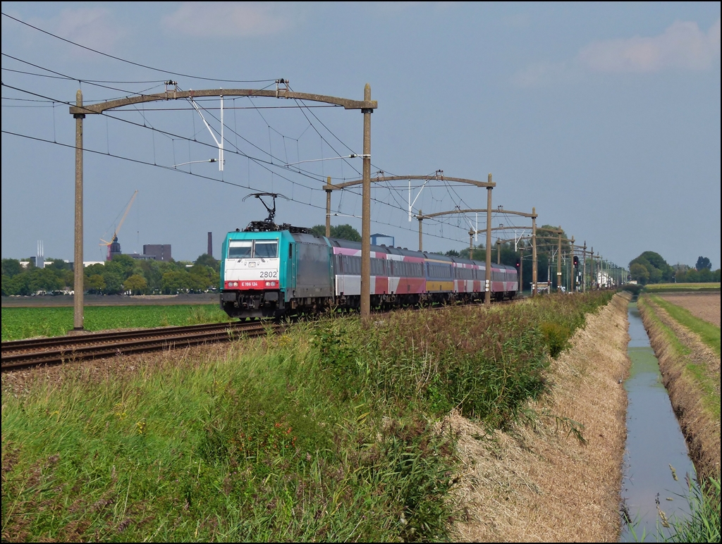 Am 03.09.2011 zieht die Traxx 2802 einen IC B (Benelux) Amsterdam – Bruxelles durch die schne niederlndische Landschaft zwischen Oudenbosch und Zevenbergen, wo es noch die tollen alten Fahrleitungsmasten gibt. (Jeanny)

Dieser stndlich verkehrende Zug, welcher die belgische Haupstadt mit Amsterdam und vice versa verband, gibt es nicht mehr. Die 7,5 Milliarden Euro teure niederlndische Hochgeschwindigkeitsstrecke sollte besser ausgelastet werden und so bestellte man in Italien (!) bei AnsaldoBreda Triebzge, welche den bewhrten IC Benelux ersetzen sollten und auf der HSL-Zuid fahren konnten. Nach 5 Jahren (!) Testfahrten, sollten die V 250 jetzt endlich am 09.12.2012 zum Einsatz kommen und zwar nicht mehr stndlich, sondern nur noch alle 2 Stunden. In der ersten Woche erreichte nur 1 Zug von 4 sein Ziel. Viele wichtige Bahnhfe werden nicht mehr bedient (Roosendal, Dordrecht, Den Haag) und zu allem bel brauchen den Fahrgste fr jede Fahrt mit dem Fyra eine Reservation. Da diese Zge besonders in den Niederlanden tglich von vielen Pendlern benutzt werden, grenzt das schon an Schikane. 

Die Tatsache, dass die niederlndische Hauptstadt nicht mehr von diesem Zug bedient wird, war wohl ausschlaggebend, dass er nun wieder eingestellt wurde. Der gute alte IC Benelux soll wieder stndlich fahren, aber leider sind die Loks schon weg. Da die Traxx nur gemietet waren, wurden sie bereits an andere Gesellschaften weiter vermietet und jetzt bemht man sich die Loks wieder nach Belgien zu holen. Sie sollen am 7. oder 8. Februar zurckgefhrt werden.

Seit dem Bestehen (1980er Jahren) des IC Benelux bestand der Zug aus einer belgischen Lok und niederlndischen IC Wagen mit Steuerwagen. Damals wurde sogar extra fr diesen Zug eine Baureihe in Belgien gebaut, die Srie 11, die sich durch ihre Fargebung von den anderen belgischen Baureihen unterschied. Die sogenannte Livre Benelux (Bordeaux rot und beige) passte farblich zu den niederlndischen IC Wagen und verlieh so dem Zug ein einheitliches Aussehen. http://www.rail-pictures.com/name/train-photo/9547/gallery/Belgium~Electric+locomotives~Serie+11.html Diese schnen Loks wurden spter durch die Traxx ersetzt und die Wagen hatten auch nicht mehr alle dieselbe Farbgebung, dafr war der Zug bunter geworden und war vor allem sehr beliebt bei den Fahrgsten.
