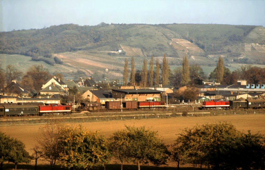 Am 06.11.1982 fotografierte Klaus Pollm�cher diese Begegnung von drei V100 im Bf Laucha. Die Lok rechts ist eine 112er vom Bw Sangerhausen und f�hrt gerade mit einem Personenzug aus Naumburg (S) Hbf ein. Die anderen zwei sind 110er. Die eine wartet mit einem Personenzug nach Naumburg (S) Hbf auf die Ausfahrt und die dritte Lok wartet mit einem Nahg�terzug, vermutlich von der Finne, ebenfalls auf die Weiterfahrt in Richtung Naumburg.