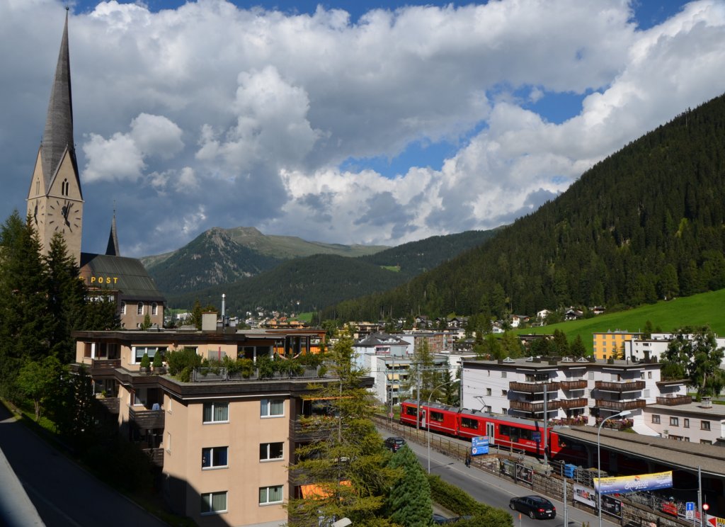 Blick vom COOP Davos auf einen ausfahrenden Regionalzug nach Chur am 10.08.2012. Der Kirchturm ist wirklich etwas geneigt (schief).