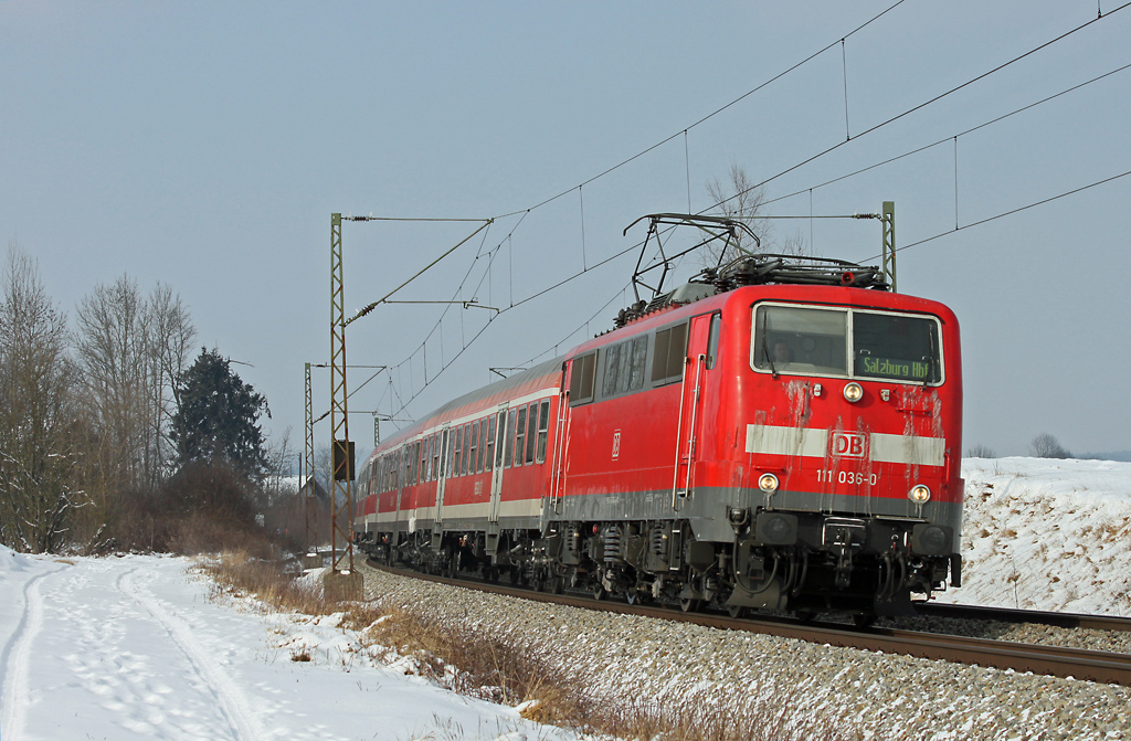 DB 111 036, geziert mit  Eisbrtchen , strebt mit ihrer Regionalbahn von Mnchen nach Salzburg dem Halt am Bahnhof Ostermnchen entgegen. Gesichtet am 11.2.2012.