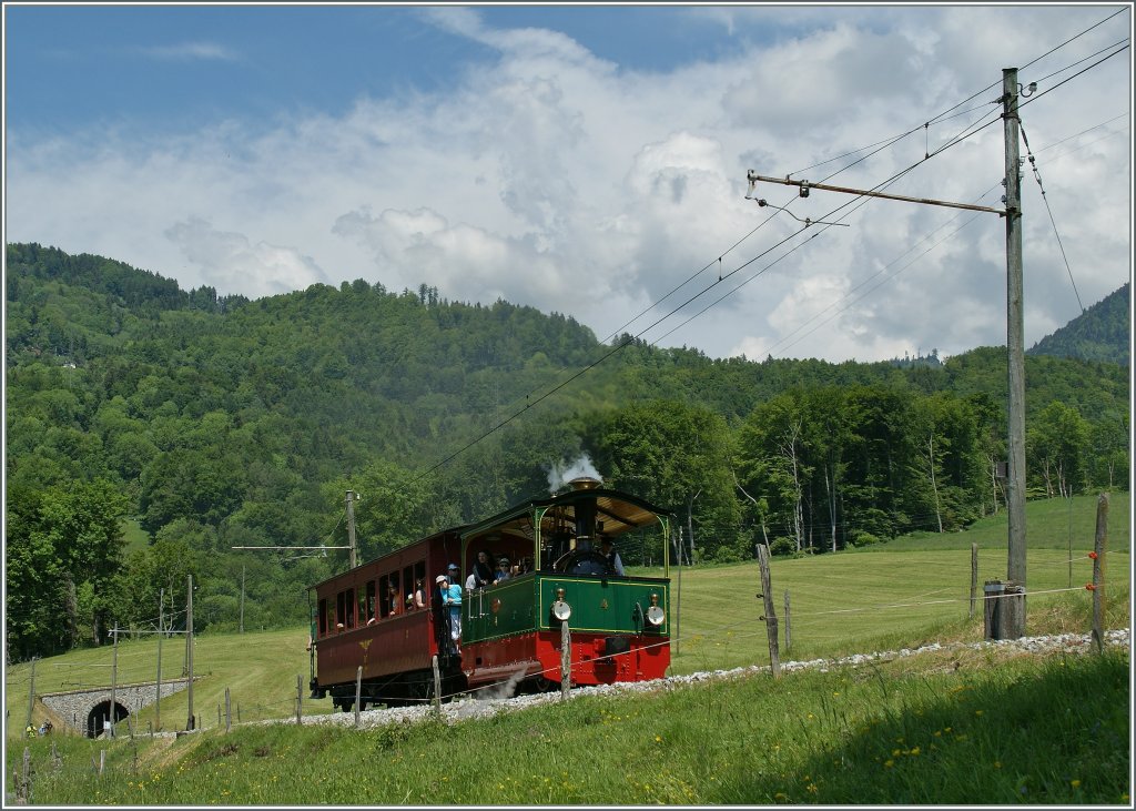 Die kleine Trambahnlok mit dem gut besetzten NStCM Wagen in der Steigung kurz vor Cornaux am 27. Mai 2012.