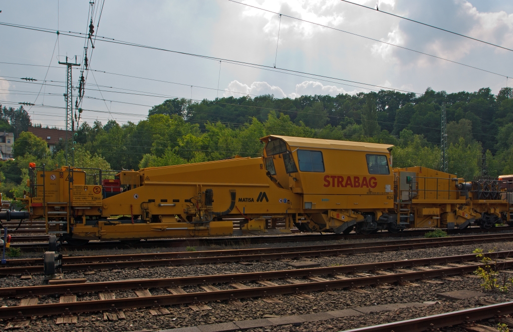 Die MATISA R24 Schotterplaniermaschine der STRABAG Rail GmbH (Schweres Nebenfahrzeug Nr. 99 80 9225 001-3 D-STRA) ist am 30.05.2012 in Betzdorf/Sieg abgestellt.

Die Maschine wurde 2009 von der MATISA Matriel Industriel S.A. in Crissier (Schweiz) unter der Fabrik-Nr. 47051 gebaut.

Die R 24 ist eine Hochleistungs-Schotterplaniermaschine auf Drehgestellen, speziell konzipiert fr den Bau und den Unterhalt der Hochgeschwindigkeitsstrecken. Ihre beiden Kehrbesen garantieren eine ausgezeichnete Kehrleistung bei einer Geschwindigkeit von +/- 6 km/h.
Der erste Kehrbesen fr die Strecke, bestckt mit einem Lngsfrderband, sammelt den berschssigen Schotter auf den Schwellen und transportiert ihn mit dem Frderband  in das15 m groe Silo. So kann berschssiger Schotter zurck gewonnen und in Bereichen mit Schottermangel verteilt werden. Die 4 unabhngige Schotterhosen unter dem Silo verteilen den Schotter vor den Pflgen, welche diesen im gleichen Arbeitsgang auf dem Gleis verteilen. Der zweite Kehrbesen, fr Weichen, ausgerstet mit einem Querfrderband, verteilt den Schotter zur linken und rechten Seite. Mit seiner sehr gerumigen Kabine, die auch an spezifische Kundenwnsche angepasst werden kann, bietet die R 24 einen groen Komfort.

Die Maschinen sind mit einem hydrostatischen Fahrantrieb ausgestattet, der einfach und bequem zu bedienen ist. Die Fahrgeschwindigkeit kann ohne Rucken durch Schaltvorgnge gesteuert werden. Das ruckfreie Fahren erhht den Komfort und ist ein Gewinn fr Mensch und Maschine, und das jeden Tag. Ein weiterer Vorteil des hydrostatischen Fahrantriebs ist, dass ein Schlupf der Rder beim Anfahren verhindert wird.

TECHNISCHE DATEN: 
Spurweite: 1.435 mm  (Normalspur)
Achsanzahl: 5 (2 Drehgestellen, eine einzelne Achse)
Achsformel: Bo´ + A1´ + 1
Lnge ber Puffer: 26.500 mm
Drehzapfen- bzw. Achsabstand: 12.500 mm / 8.000 mm
Achsabstand in den Drehgestellen: 1.800 mm
Treib- und Laufraddurchmesser: 920 mm (neu)
Hhe: 4.263 mm
Breite: 3.050 mm
Eigengewicht: 68.420 kg
Anhngelast: - t
Zur Mitfahrt zugel. Personen: 5
Hchstgeschwindigkeit (geschleppt): 100 km/h 
Hchstgeschwindigkeit Eigenfahrt: 25 km/h (nur als Rangierfahrt)
Max. Geschwindigkeit beim Planieren: 15 km/h
Max. Geschwindigkeit beim Kehren: 6 km/h     
Zugelassen ab Streckenklasse: C2 
Kleinster befahrbarer Kurvenradius:  R 250 m  (Fahrzeug allein 90 m)
Min. Radius bei Arbeit: R 190 m
Bremse: 2 x KE-GP (K), Max. 57 t
Dieselmotor:  DEUTZ wassergekhlter V8-Zylinder-Viertakt- Dieselmotor mit Turboaufladung, Ladeluftkhlung, Vierventiltechnik und wassergekhlte Abgasrohre vom Typ DEUTZ BF 8 M 2015 CP 
Motorleistung: 440 kW (598 PS) bei 2.100 U/min
Motorhubraum: 15,9 Liter (Bohrung 132 mm / Hub 145 mm)
Motorgewicht: 1.060 kg
Gre Schottersilo:15 m  (Standard 10 m)
Tankvolumen: 3.000 Liter  (Standard 2 m)

Bemerkung: Laut Prospekt von Matisa kann die Maschine in Eigenfahrt auch 100 km/h schnell fahren (dann hat sie nur 2 Achsen angetrieben), aber laut Anschriftentafel ist eine Eigenfahrt nur als Rangierfahrt mit 25 km/h zugelassen.
