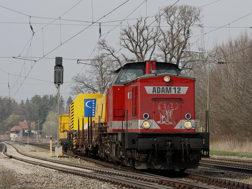 Die V 100 von Uwe Adam am 04.04.2009 mit einem Bauzug bei der Durchfahrt in Aling.
