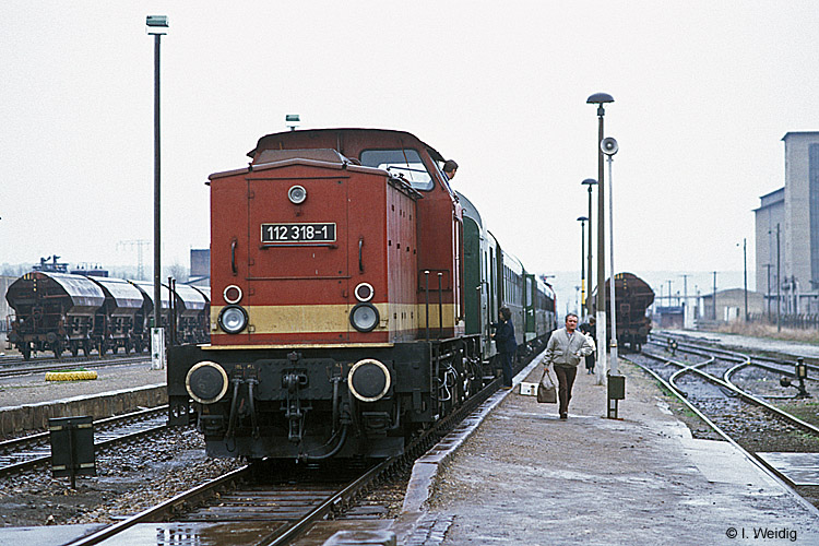 DR 112 318-1 mit dem P 15216 von Naumburg Hbf nach Artern, am 21.03.1991 im Bahnhof Vitzenburg. Die Lok wurde unter Eisenbahnern auch  Garagenlok  genannt, da sie so gepflegt wurde, dass man vom Fu�boden essen konnte. Am Ende des Zuges h�ngt die 110 059-3, die den hinteren Zugteil ab Nebra zur�ck nach Naumburg fahren wird. (Foto: Ingmar Weidig)