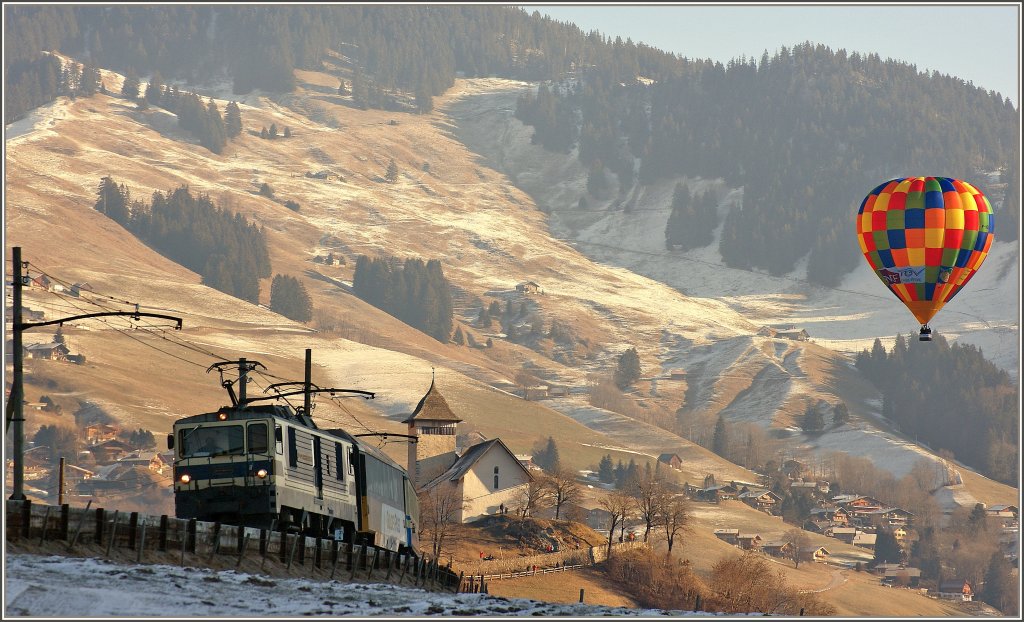 Ein Ballon setzt farbige Akzente als ein Goldenpass-Panoramiczug in Richtung Montreux Chteau d'Oex verlsst.
(23.01.2011)