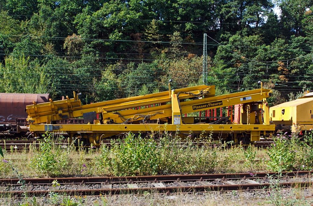 
Plasser & Theurer Beladestation BLS 2000 (Schweres Nebenfahrzeug Nr. 97 19 26 502 57-8) der Hering Bau, Burbach, abgestellt am 25.08.2012 in Betzdorf/Sieg.
Um Schüttgüter mittels Erdbaugeräten (Bagger etc.) in MFS-Einheiten fördern zu können, ist die Beladestation entwickelt worden. Sie besteht aus 
Schottertrichter, breitem Kettenförderband und hydraulisch ein- und ausfahrbarem Übergabeförderband mit Schwenkeinrichtung für die 
Arbeit im Gleisbogen. Die BLS 2000 ist ein zweiachsiges, gleisfahrbares Gerät. Zur leichten Beladung kann der Schottertrichter während 
der Arbeit hydraulisch abgesenkt werden. 

Technische Daten:
Achsanzahl: 2
Eigengewicht:  22.300 kg
Länge über Puffer: 12.900 mm
Achsabstand: 8.000 mm
Höchstgeschwindigkeit: 100 km

