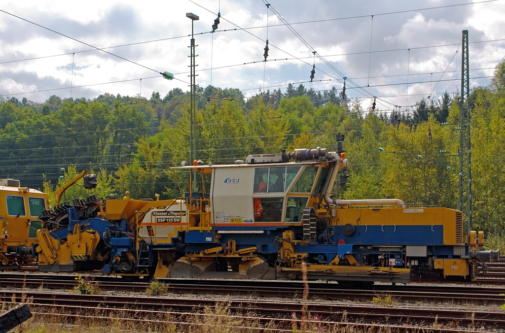 Plasser & Theurer Schnellschotterplaniermaschine SSP 110 SW  (Schweres Nebenfahrzeug Nr. 97 16 46 509 18-4) der DGU - Deutsche Gleisbau Union (Koblenz), abgestellt am 22.09.2012 in Betzdorf/Sieg. Techn. Daten:  Gesamtlnge ber Puffer 17.500 mm  >  Anzahl der Achsen 2  >  Gewicht 44.000 kg  >  Max. Eigenfahrgeschwindigkeit 100 km/h   >  Leistung 400 kW  (Deutz BF8M 1015C Motor)  >  Spurma 1.435mm  >  zugelassen fr Streckenklasse D4 oder hher. 

Die Schotterverteil- und Planiermaschinen SSP 110 SW stellen den erforderlichen Regelbettungsquerschnitt in Gleisen und Weichen her. 
Die Maschinen verfllen, planieren und kehren das Gleis.
Sie verfgen ber Besenwellen fr alle Oberbauformen. Diese Maschine hat ein Steilfrderer der berschssiger Schotter in das Silo frdert,  woraus der Schotter bei Bedarf dem Gleis dosiert wieder zugefhrt wird.