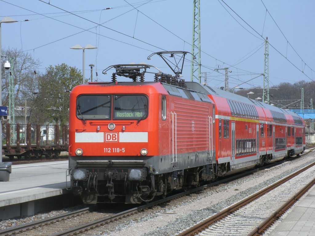 RE 13010 Sassnitz-Rostock,am 21.April 2012 gefahren von der Rostocker 112 118-5 und Rostocker Dostos beim Halt in Bergen/Rgen.