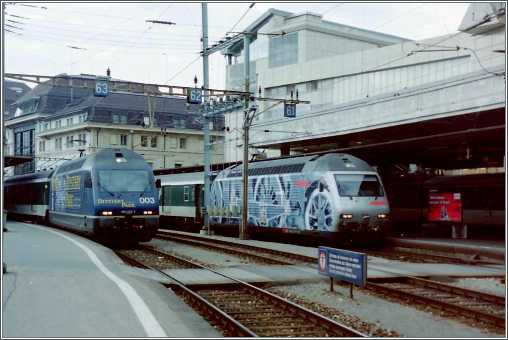 SBB Re 460 042-5 auf Gleis 1 mit einem IC nach St. Gallen und die BLS Re 465 003-2 mit einem IR nach Brig auf Gleis drei in Lausanne im Frhjahr 2000.