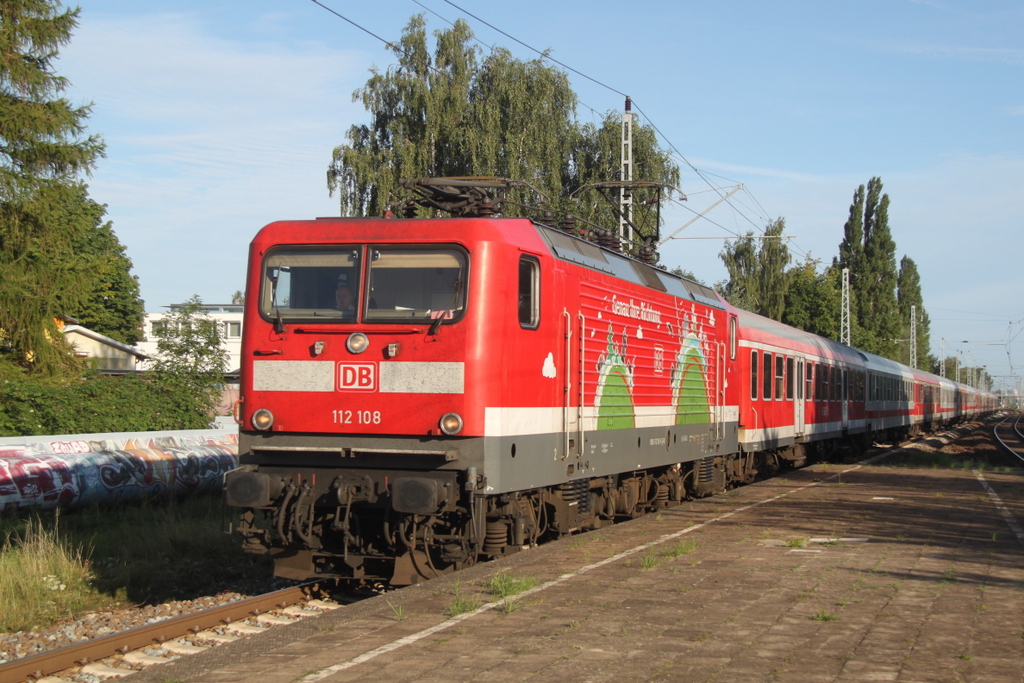 112 108-6( Genau Ihre Richtung ) mit dem Pommes Rot-Wei Express 13290 von Warnemnde nach Berlin-Ostbahnhof bei der Durchfahrt am 29.08.2015 im Haltepunkt Rostock-Holbeinplatz