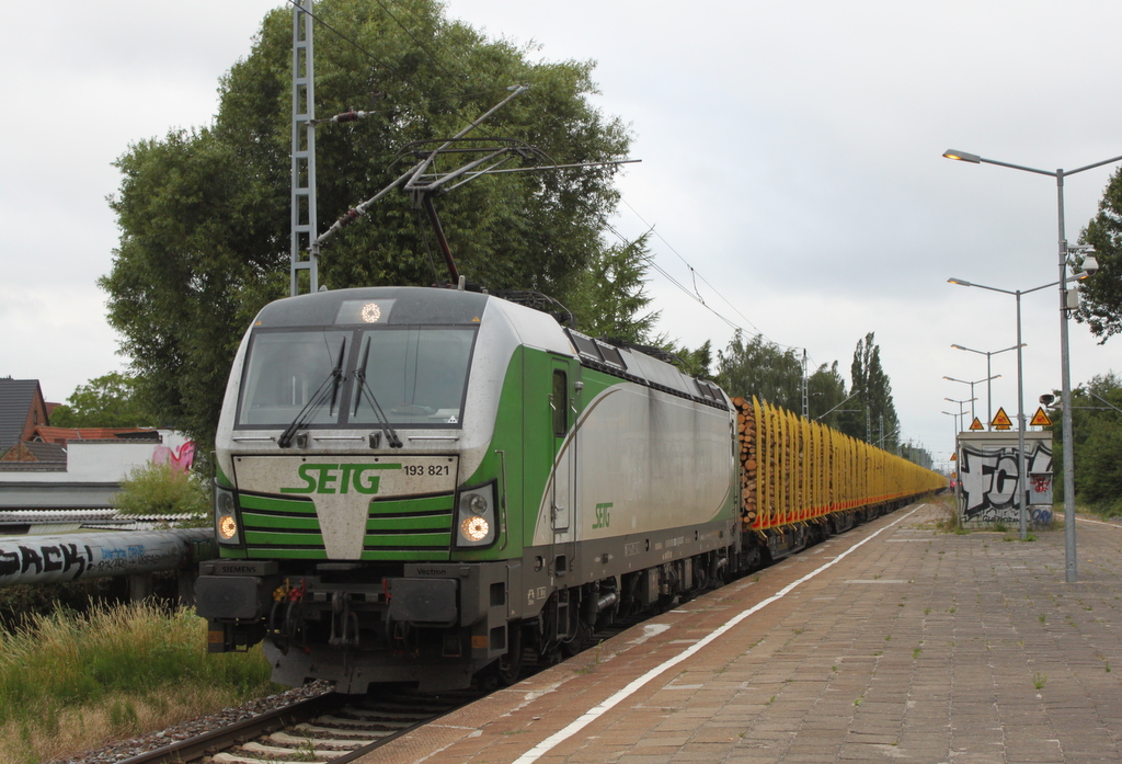 193 821 mit Holzzug von Rostock-Bramow nach Stendal-Niedergörne bei der Durchfahrt im Haltepunkt Rostock-Holbeinplatz.06.07.2018