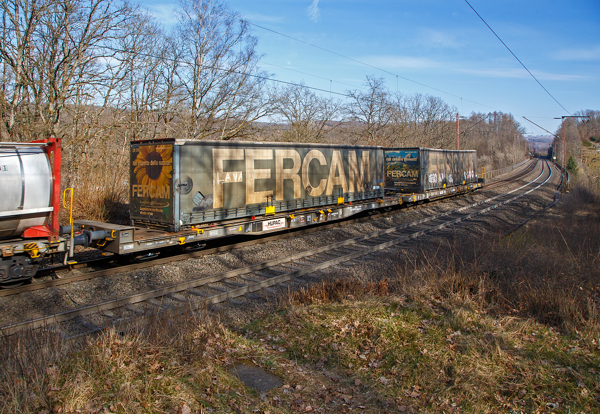 Achtachsiger niedrig gelegte Doppelwagen Jumbo II / Mega II (Trag-/Taschenwagen-Doppeleinheit) der Gattung Sdggmrrss, 83 85 4933 297-9 CH-HUPAC, der Hupac Intermodal SA, am 13.03.2022 im Zugverband bei einer Zugdurchfahrt bei Wilnsdorf-Rudersdorf. Hier beladen links mit einer FERCAM Sattelzug-Wechselbrücke und rechts (hinten) mit einem FERCAM Sattelzugauflieger.

Diese Wageneinheiten bestehen aus einer niedrigen Tragwagenhälfte für Container und Wechselbehälter („CT“) und einer niedrigen Taschenwagenhälfte („SK“). Die beiden Wagenhälften sind mit einer, im Normalbetrieb nicht zu trennenden, (von den Waggons der RoLa, Saadkms 690, abgeleiteten) Kurzkupplung verbunden.

Der niedrig gelegte Doppelwagen Mega II ist fast 37 Meter lang. Er wurde 2003 eingeführt und ist heute auf allen Shuttle Net-Relationen der HUPAC im Einsatz. Der Mega-Wagen ermöglicht den Transport von Standard- und Megatrailern mit einer verfügbaren Innenhöhe von 2,55 bis 3,0 Metern je nach Streckenprofil. Durch die niedrig gelegte Ladefläche können C 70-400 kodifizierte Jumbo-Wechselbehälter bis Norditalien und High-Cube-Container bis Süditalien auf der Gotthardstrecke transportiert werden.

Zusätzlich der Eignung für die neuen Megatrailer, wegen deren Umschlagtechnik mittels tiefliegenden Greifkantenbeschlägen ein sehr niedrig aufbauender Wagenrahmen erforderlich ist, sollten auch Container und Wechselbehälter mit großen Höhenmassen alpenquerend befördert werden können. Damit war ein über die Ladelänge nicht in der Höhe gekröpfter Wagenrahmen erforderlich. Die verglichen mit der „Standardhöhe“ von 1.175 mm über Schienenoberkante (SOK), sehr niedrige Aufstandshöhe von nur 855 mm des MEGA II machte den Einsatz von Drehgestellen der Bauart Y31 Lsi(f) notwendig. Diese weisen eine geringere Bauhöhe, durch kleinere Radsätze mit 760 mm Laufkreisdurchmesser und maximal 18 t Radsatzlast, auf.

Hersteller dieser Wagen ist die Ferriere Cattaneo in Giubiasco (Schweiz), die 115 Wagen (230 Wagenmodule) hergestellt hat.
