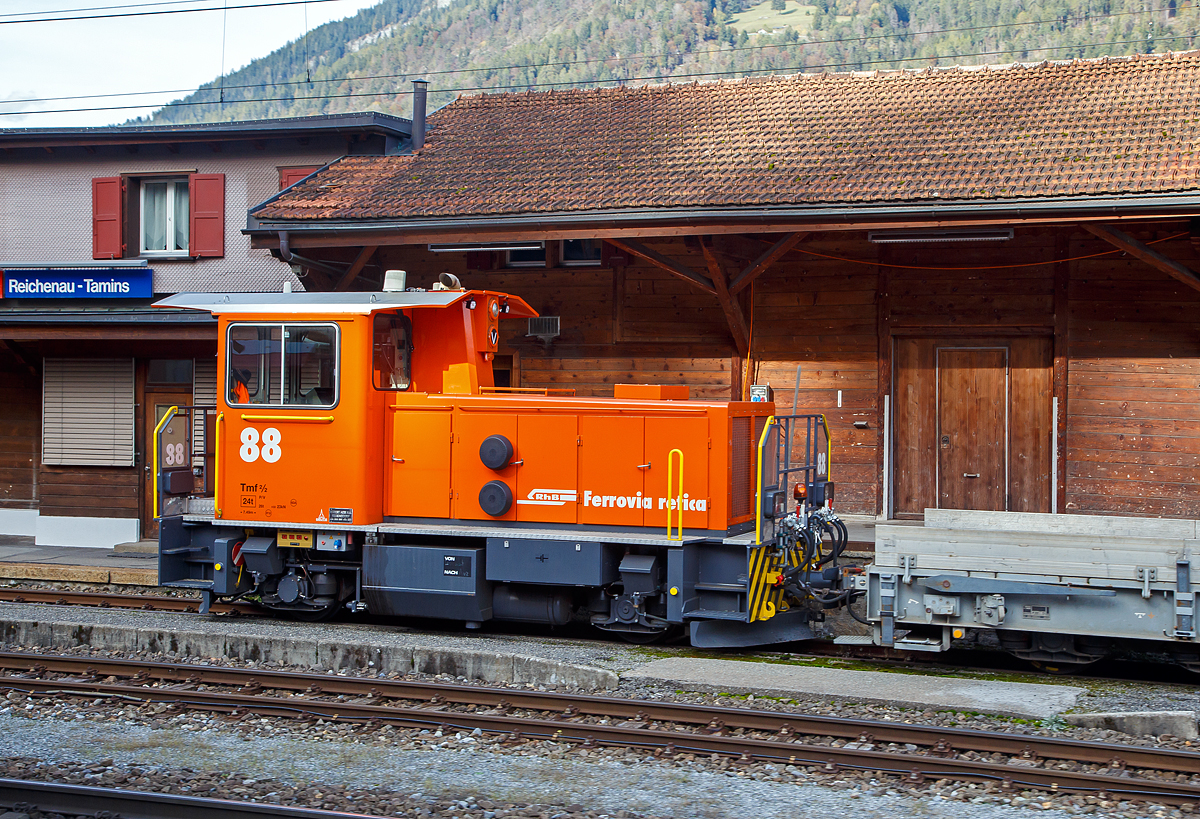 Äußerlich sieht er noch so aus wie der Alte, aber innerlich ist er komplett neu....
Der der aus dem Refitrprogramm gekommene RhB Tmf 2/2 88 ist am 01.11.2019 im Bahnhof Reichenau-Tamins abgestellt, aufgenommen aus einem RhB Zug heraus.

Die Tmf 2/2  wurde 1992 von RACO (Robert Aebi AG, Regensdorf, Schweiz) unter der Fabriknummer 1989 gebaut und an die RhB geliefert. Die RACO Typenbezeichnung ist 420 CT 4H.Die Tmf 2/2 sind die mit Funkfernsteuerung ausgerüsteten Traktoren mit Verbrennungsmotoren der Rhätischen Bahn (RhB). Zwischen 1991 und 1994 wurden von RACO sechs dieser Tmf 2/2 mit den Nummern 85 bis 90 beschafft. Der Tmf 2/2 88 wurde nach dem Umbau in der RhB Werkstatt in Landquart Anfang Oktober 2018 erfolgreich durch das BAV abgenommen und durfte einige Tage später den Betrieb aufnehmen.

Die RhB Tmf 2/2 88 ist der Prototypenumbau, die im Rahmen des Projekts «Refit Baudienstfahrzeuge Tm(f) 2/2» werden die sechs Rangiertraktoren Tmf 2/2 85-90 mit den Baujahren1990 bis 1994, nach und nach, durch diverse Umbau- und Erneuerungsarbeiten fit für die Zukunft gemacht. Zu immer höheren Unterhalts- und Revisionskosten führen nach den Jahren im Betrieb einige Komponenten aus dem Antriebsstrang und dabei vor allem der Cummins-Dieselmotor. Aufgrund seines Alters kann dieser Motorentyp nicht mehr als Neuteil beschafft, sondern nur noch revidiert werden.

Aus diesem Grund hat sich die RhB vor einigen Jahren entschieden, diesen Dieselmotor bei den Tmf 2/2 85-90 zu ersetzen. Nach umfangreichen Untersuchungen wurde bald klar, dass nebst dem Dieselmotor auch einige andere zentrale Fahrzeugkomponenten von Obsoleszenz betroffen sind und weitestgehend nicht mehr den heutigen technischen Ansprüchen genügen. Dazu gehören Getriebe, Partikelfilteranlage, Kühlungsanlage, Hydraulik, Pneumatik, Bremsmechanik wie aber auch die komplette elektrische Einrichtung, die Fahrzeugsteuerung, die Sicherheitseinrichtung und die Fahrdatenvisualisierung. Grob umschrieben in etwa alles außer dem Chassis, Kabine und Achsen.

Antriebsstrang:
Aufgrund der betrieblichen Anforderungen entschied die RhB, den Reihen 6-Zylinder durch einen V8-Dieselmotor von Deutz zu ersetzen. Der neue Motor ist dank seiner V-Bauweise sehr kompakt und kann je nach Drehzahl bis zu 30 % mehr Leistung abgeben als der bestehende. Um diese Leistung optimal auf die Schienen zu bringen, wurde das bestehende Lastschaltgetriebe durch ein automatisches Wendegetriebe der Firma Voith ersetzt. Dieses Getriebe sowie auch die komplette Kühlanlage wurden von Voith auf die Leistungsdaten des Motors optimal abgestimmt. Ein großer Benefit nebst der Leistungssteigerung und der „Einfachheit“  des Antriebsstranges liegt darin, dass die Gangschaltung – mit welcher die restlichen Tmf  2/2 gestraft sind – nicht mehr von Relevanz ist. Dank dem neuen Automatikgetriebe lässt sich die Geschwindigkeit stufenlos und ohne Leistungseinbruch zwischen V null und V max einstellen.

Fahrzeugsteuerung und Fahrdatenvisualisierung
Die bestehende KraussMaffei-Fahrzeugsteuerung wurde durch eine von Selectron, die RhB-Standard ist, ersetzt. Die Antriebsstrangkomponenten (Dieselmotor / Getriebe) wie auch Fahrzeugkomponenten wie beispielsweise Display, Funkfernsteuerung usw. kommunizieren über einen Fahrzeugbus mit der Fahrzeugsteuerung. Dadurch erleichtert sich die Fehlerdiagnose und es konnten viele elektromechanische Komponenten eingespart werden. Die Fahrzeugdaten werden dem Lokführer über Displays visualisiert.

TECHNISCHE DATEN der RhB Tmf 2/2 88 (Refit):
Baujahre: 1991/92 und 1994
Spurweite: 1.000 mm (Meterspur)
Achsfolge: B
Länge über Puffer:  7.490 mm
Achsabstand: 3.750 mm
Breite: 2 700 mm
Eigengewicht:  24 t
Höchstgeschwindigkeit: 60 km/h (60 km/h Schleppfahrt)
Treibraddurchmesser: 	750 mm
Motorentyp: Deutz V8-Dieselmotor 
Weitere Daten wie auch Motor- und Getriebetyp sind mir leider noch unbekannt.
