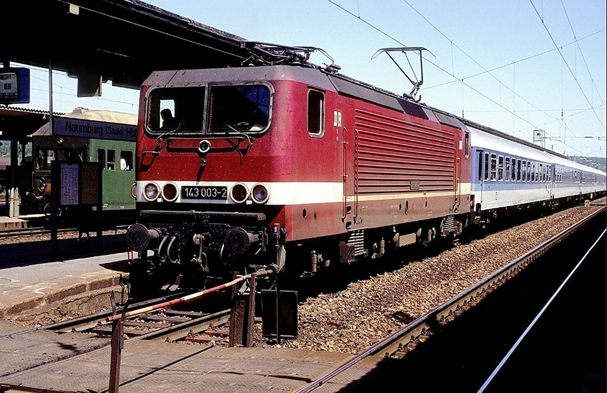 Am 01.07.1993 steht dieser aus InterRegio-Wagen gebildete Schnellzug D 1452 von Berlin-Lichtenberg nach Frankfurt (M) Hbf mit der DB 143 003-2 in Naumburg (S) Hbf. Am Nachbarbahnsteig steht der P 7325 nach Saalfeld (S). (Foto: Biesdorfer83)