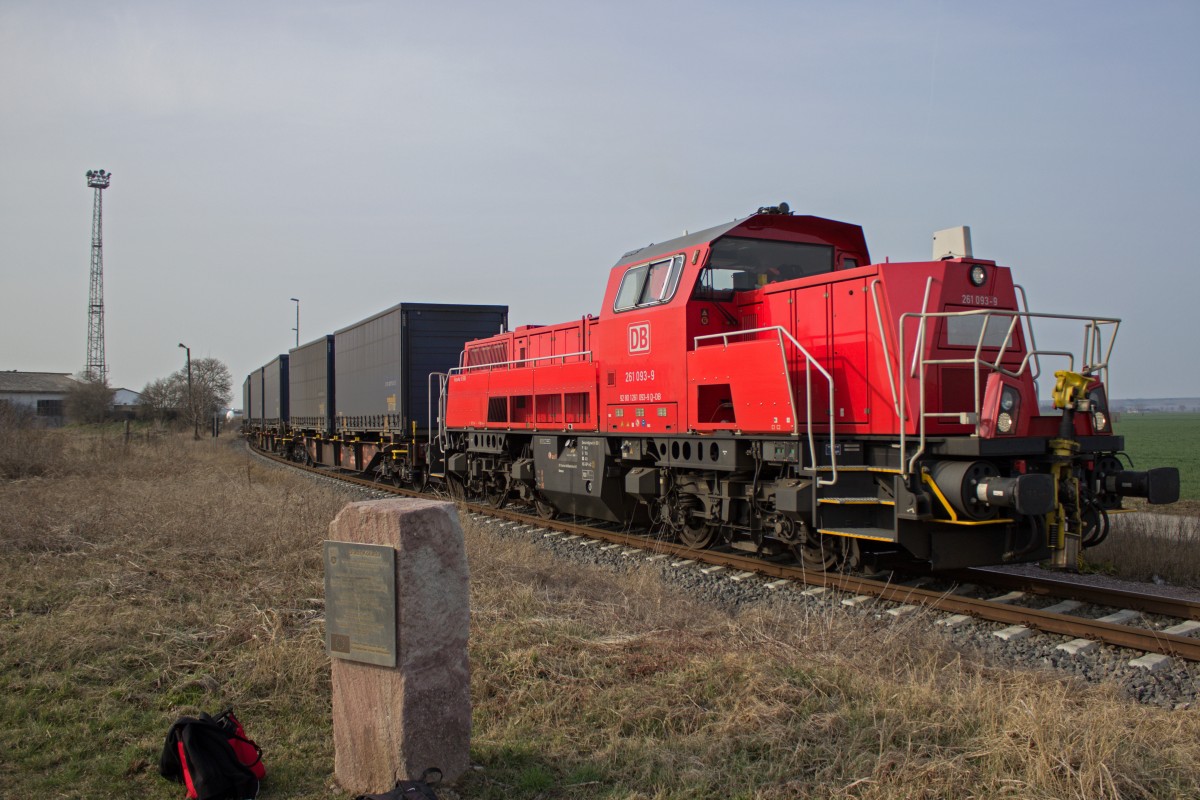 An einem Stein, der an die für den Kölledaer Anschluss verwendeten EU-Mittel erinnert, vorbei, schiebt 261 093 ihren Übergabezug in Richtung Motorenwerk.