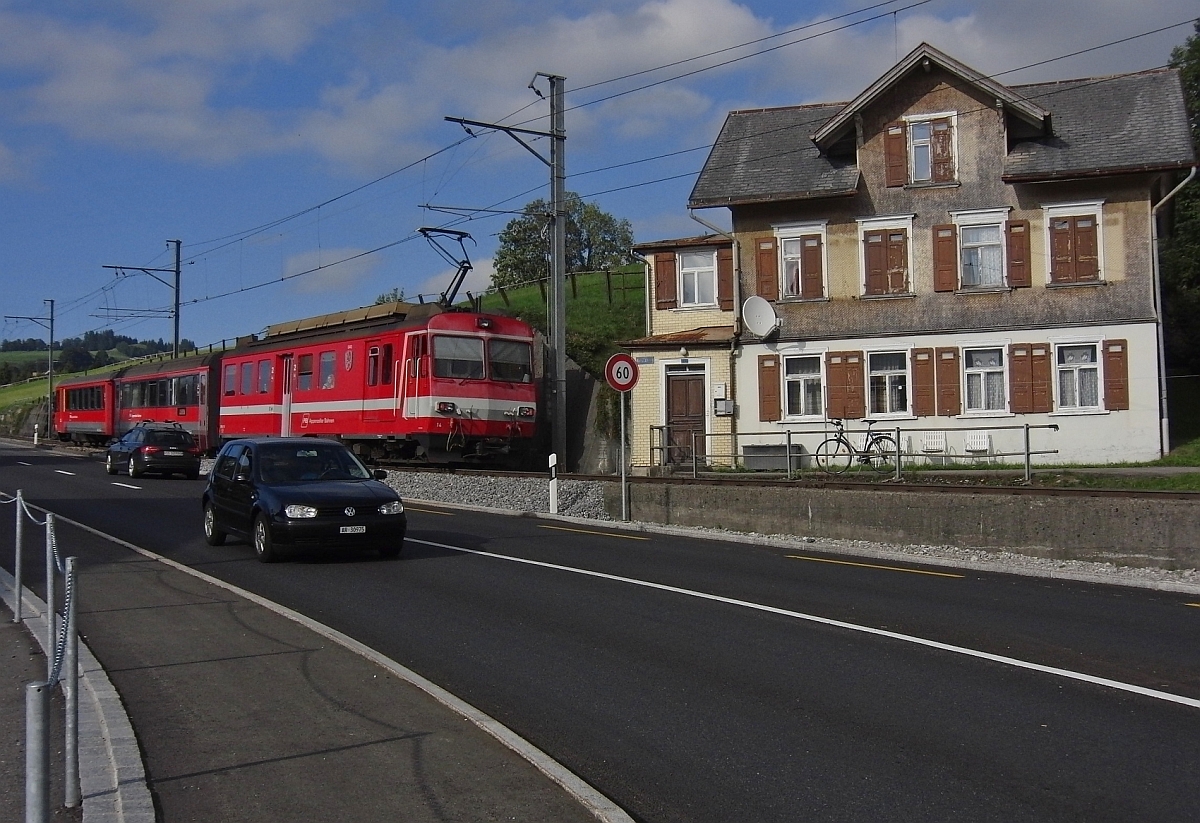 Bei einem Groteil der Strecke zwischen Appenzell und St. Gallen liegen die Gleise der Appenzeller Bahn parallel zur Strae. Wie auch hier in Hirschberg, wo S11 2166 nach St. Gallen gerade die gleichlautende Haltestelle verlassen hat (21.09.2013).