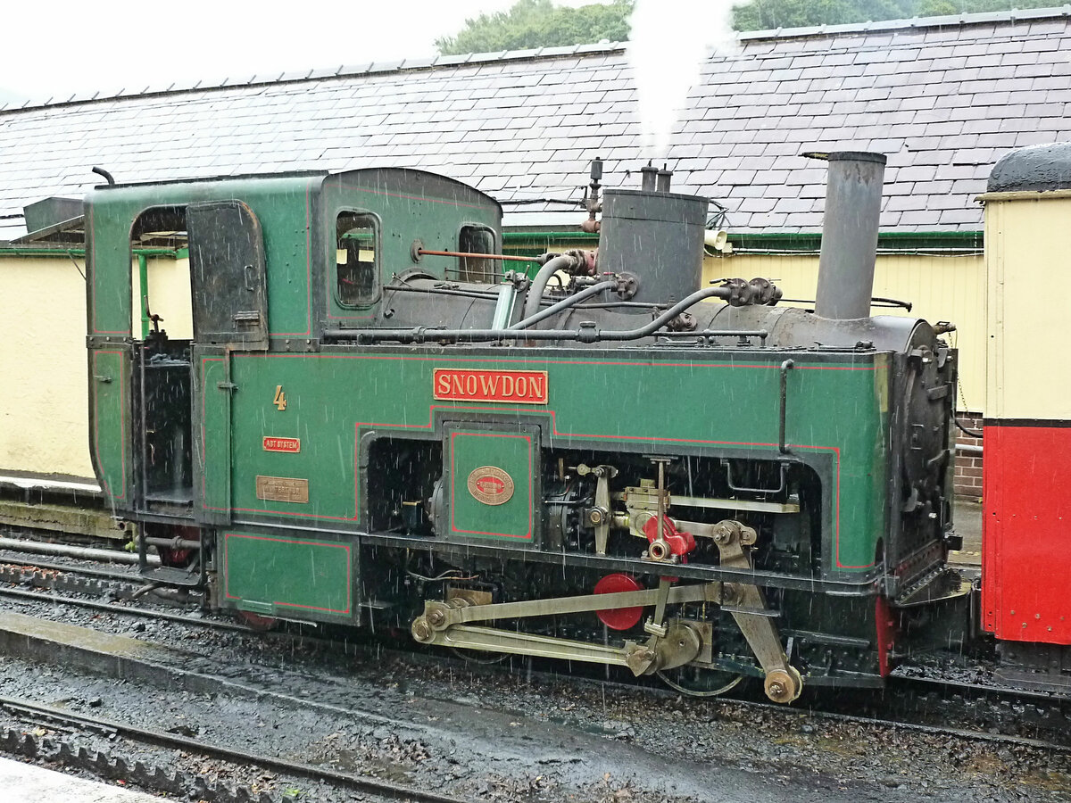 Da eine Lok der Brienz Rothorn Bahn 2018 die Snowdon Mountain Railway in Wales besuchte, hier einige Bilder dieser 7, 6 km langen Zahnradbahn mit ihren schweizerischen Loks. Die Bahn wurde 1896 eröffnet und erhielt 5 Dampflokomotiven von SLM Winterthur, 1 - 5. Lok 1 verunfallte am Eröffnungstag und erlitt Totalschaden. Neben den verbliebenen alten Loks 2 - 5 wurden 1922/23 3 neuere Loks von SLM beschafft (6 - 8). 1986-92 wurden in England 4 kleine Dieselloks 9 - 12 erstellt, doch danach gab es nur Misserfolg, zuerst mit drei Triebwagen (1995), die sich nicht bewährten, und jetzt mit zwei Diesel-Hybrid-Loks mit langem Rahmen, der auch Personenabteile aufnehmen kann; 2022 wurden diese Loks wegen ungenügender Energieproduktion an den Hersteller zurückgegeben. Von den Dampfloks dürften heute 2 Originalloks (Nr. 3 und 5) and 1 Lok von 1922 (Nr. 6) betriebfähig sein und zuschlagspflichtige Züge führen. Im Bild steht Lok 4 in Llanberis; ihre Tafeln weisen auf SLM Winterthur 1896 und eine Aufarbeitung in England 1963 hin. 6.Juli 2012. Die Wengernalpbahn WAB erhielt vier gleichartige Lokomotiven, Nr. 9 bis 12 (während die für die WAB etwas später gelieferten 13-14 gewisse Aehnlichkeiten mit den späteren Snowdon-Loks besassen).  