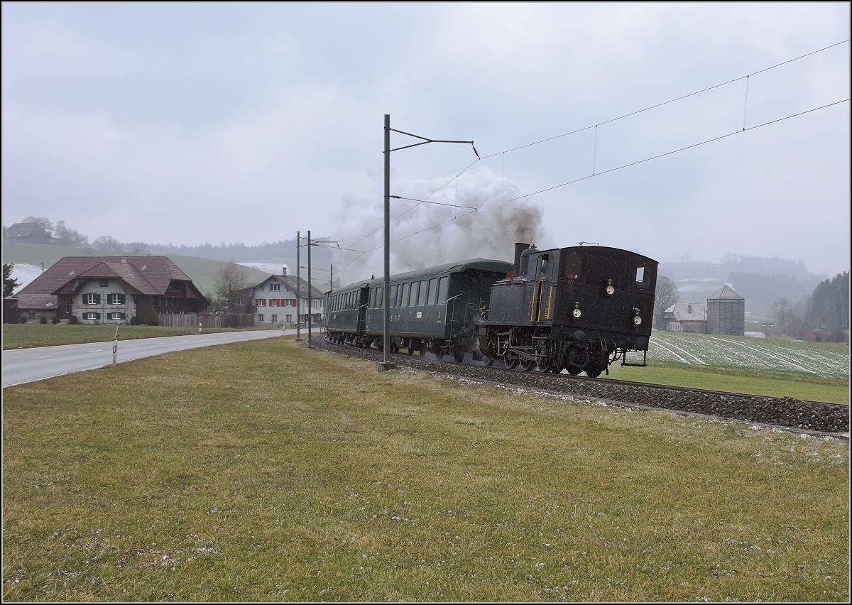 Dampflok Ed 3/4 Nr. 2 der Solothurn-Münster-Bahn bei Häusernmoos. Betreut wird die Lok durch den Verein historische Emmentalbahn. Mit im Gepäck hat sie zwei vierachsige Leichtstahlplattformwagen und einen K2. Februar 2018. 