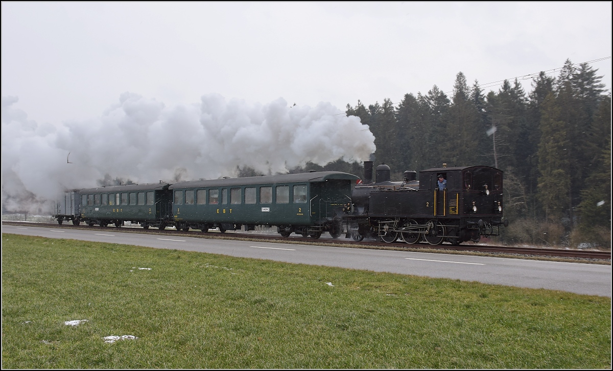 Dampflok Ed 3/4 Nr. 2 der Solothurn-Münster-Bahn bei Häusernmoos. Betreut wird die Lok durch den Verein historische Emmentalbahn. Mit im Gepäck hat sie zwei vierachsige Leichtstahlplattformwagen und einen K2. Februar 2018. 