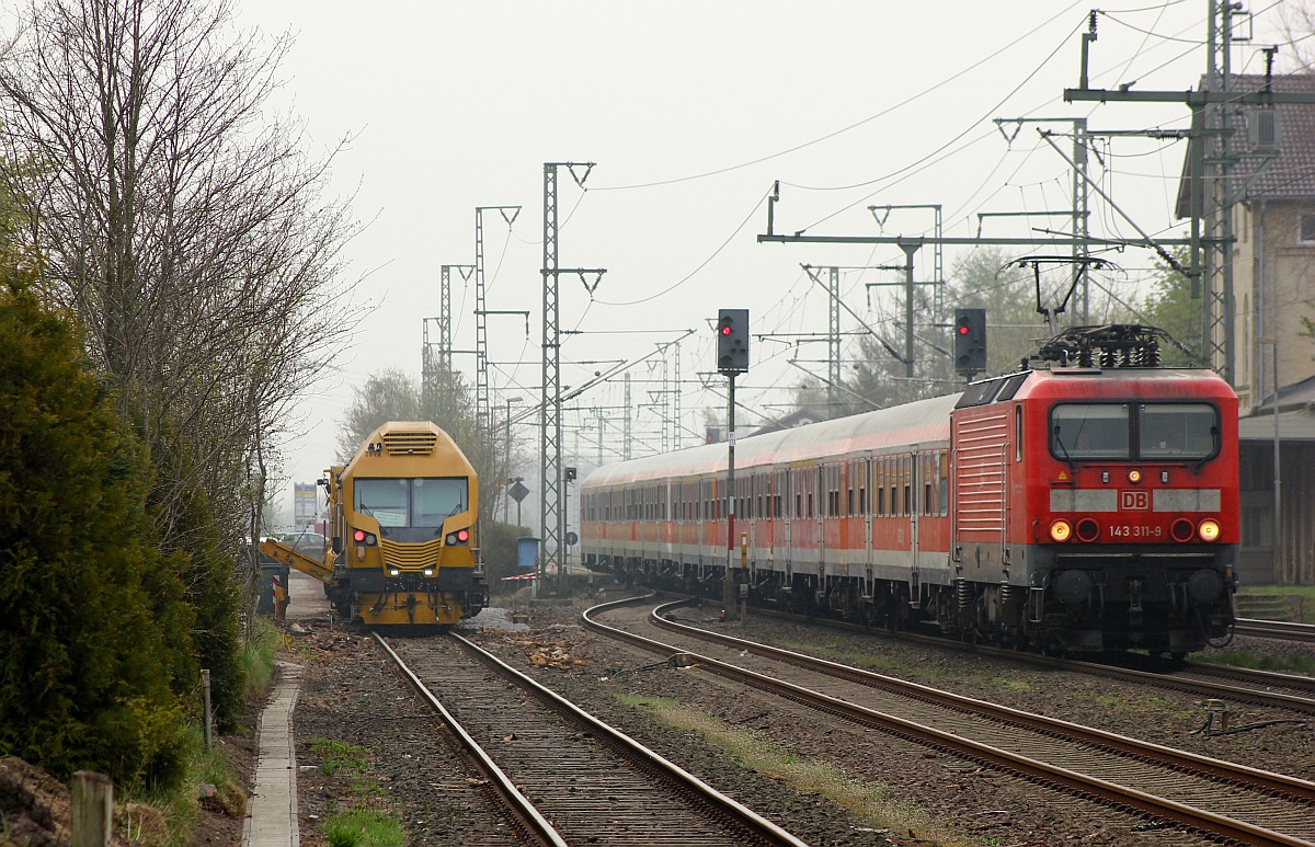 DB 143 311-9 verlässt hier mit dem RE7 nach Flensburg den Haltepunkt Jübek. Links steht der Linsinger Schienenfräszug in der Ladestrasse. 26.04.2015