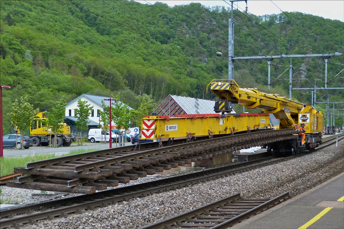 Der 150 t Kirow Gleis- und Weichenbaukran KRC 1200 (ein Kirow MULTI TASKER KRC 1200) 99 81 9119 004-5 der Firma Swietelsky hat 2 alte Gleisstücke am Hacken, die er aus dem Schotter im Bahnhofsbereich von Kautenbach gehoben hat und nun zum Ablageplatz tranportiert. 14.05.2016 (Hans)