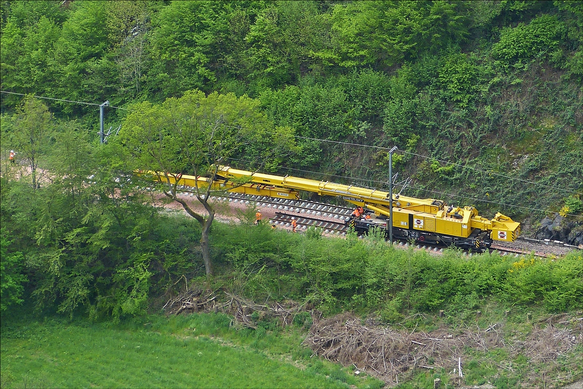 Der 150 t Kirow Gleis- und Weichenbaukran KRC 1200 (ein Kirow MULTI TASKER KRC 1200)  99 81 9119 004-5 der Firma Swietelsky bei Gleisbauarbeiten im Bahnhof Kautenbach. Auf dem Foto hat der Kran den Tunnel mit seiner Last durchfahren und wird in krze das Gleisstck an das Ende des bisher verlegtem Gleis ablegen.  16.05.2016 (Hans)