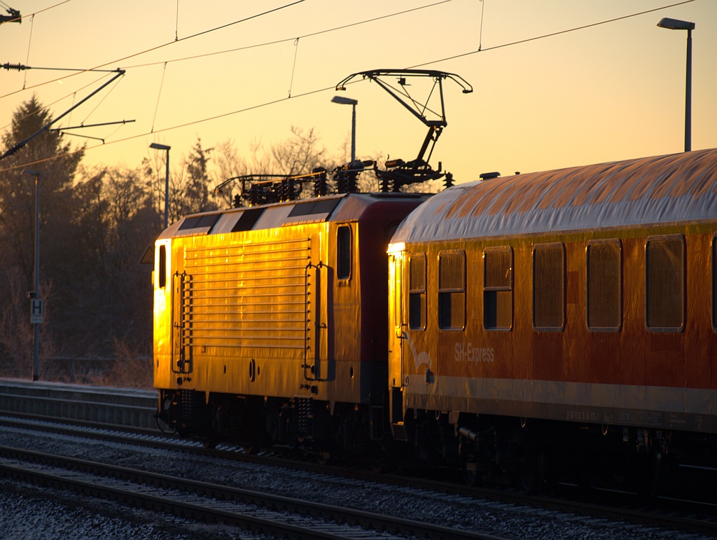 Der aufgehenden Sonne entgegen verlässt hier die 112 153 mit dem SH-Express nach Hamburg den Bahnhof von Schleswig. 28.01.2011