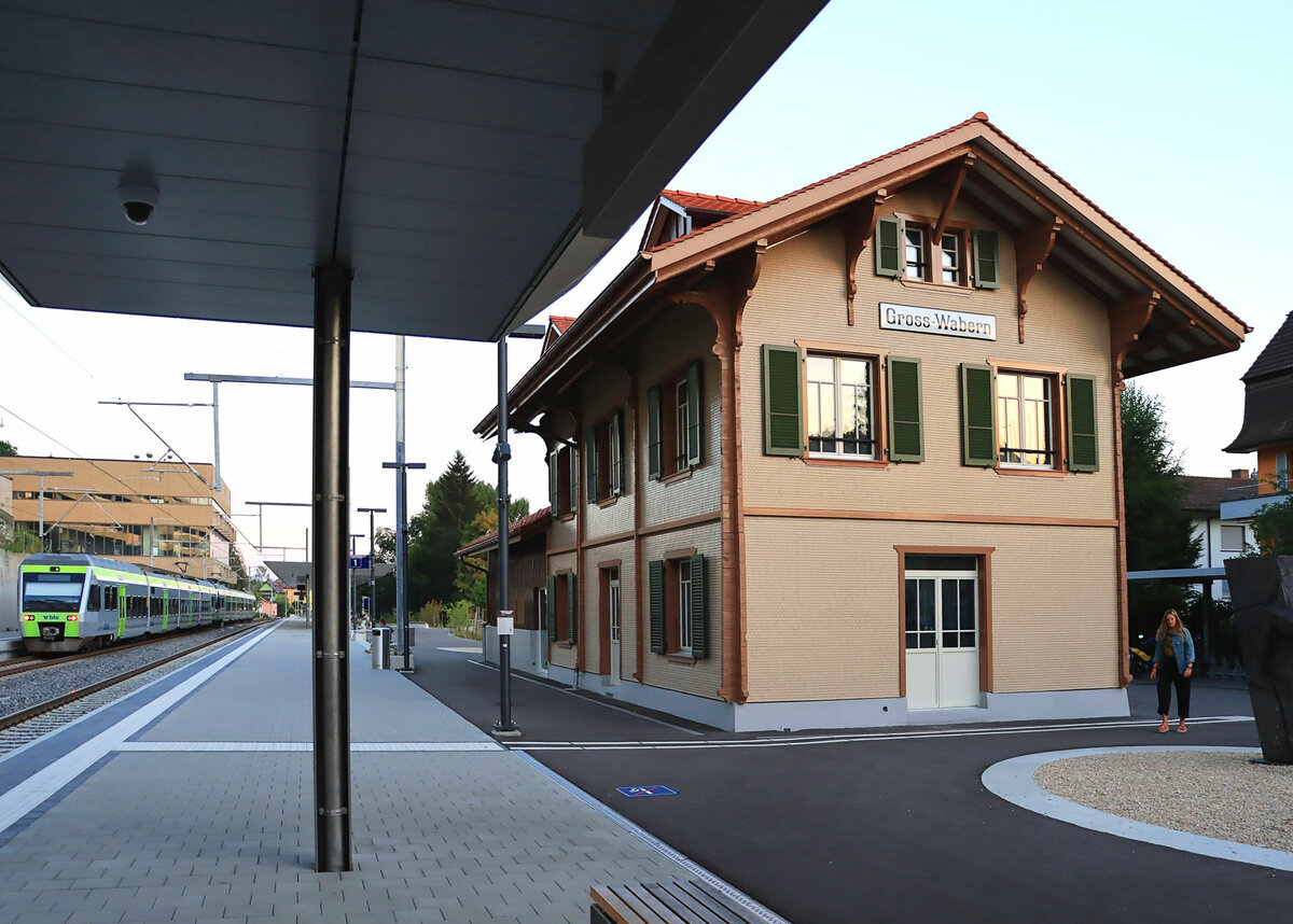 Der Bahnhof Wabern bei Bern einst und jetzt: Hier nach der Restauration am 16.August 2022, angeschrieben  Gross-Wabern . Daneben fahren zwei NINA (017 + 023) als S4 nach Solothurn/Sumiswald ohne Halt durch. 