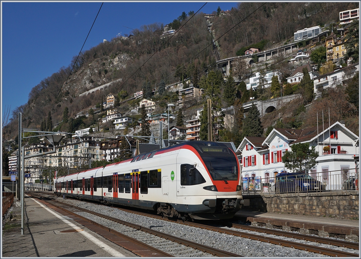 Der FLIRT 523 013 als S2 auf der Fahrt nach Villeneuve beim Halt in Territet. In der Bildmitte deutet die markante Bogenmauer den Verlauf der Rochers de Naye Bahn an, und auch die Standseilbahn von Territet nach Glion ist zu erkennen. 
27. Feb. 2017