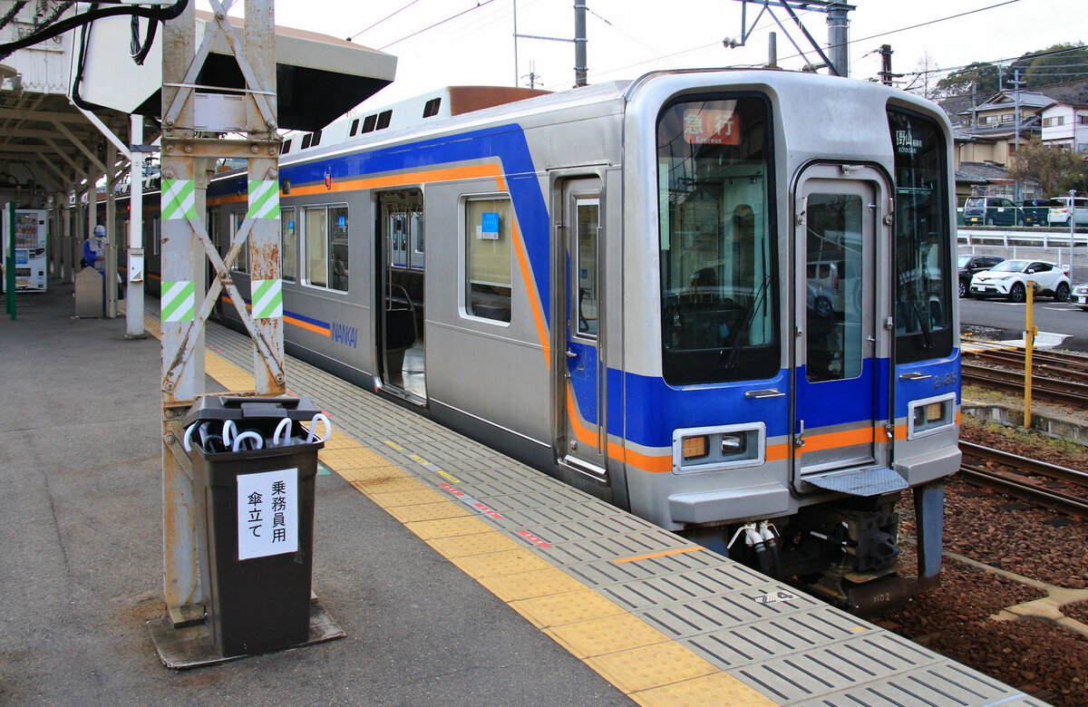 Der Nankai-Konzern, Partnerbahn der MOB: Am Ausgangspunkt der Bergstrecke wartet Zug 2185 - 2035 in Hashimoto auf die Abfahrt Richtung Kôya-san. Ein Blick in den Wagen zeigt die recht einfache aber dennoch bequem gepolsterte Inneneinrichtung mit Längssitzen der Wand entlang. Hübsch ist der schwarze Kasten voller weisser Regenschirme; die Aufschrift leutet:  Ständer für Schirme für das Bahnpersonal . 28.März 2017   