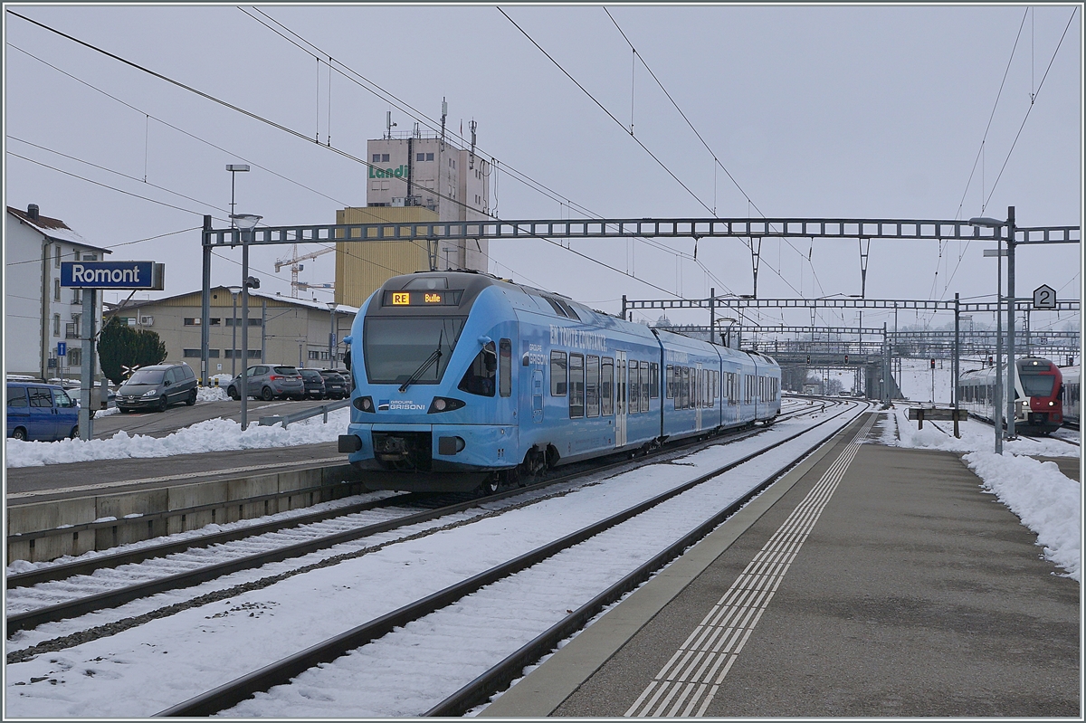 Der im sehr gefälligen Werbeanstrich der  Groupe Grisoni  gehaltene TPF RABe 527 198 verlässt Romont in Richtung Bulle. 

22. Dezember 2021