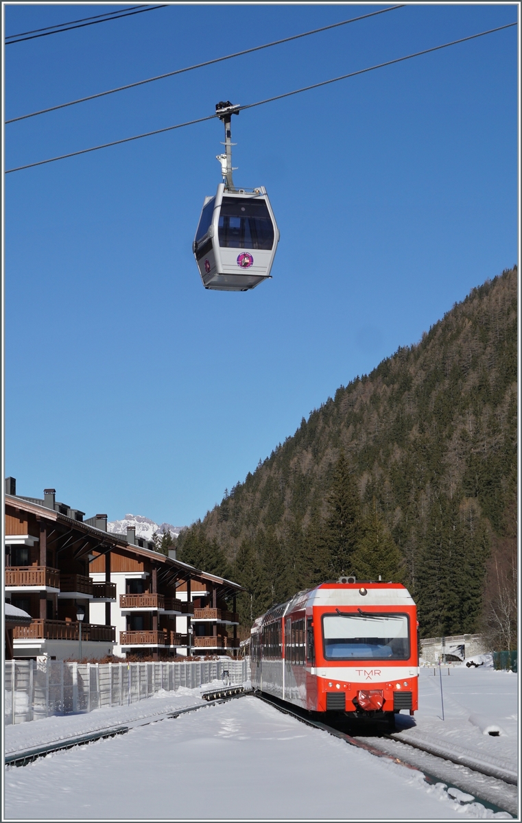 Der TMR Beh 4/8 71 erreicht sein Ziel Vallorcine, während hin der Höhe eine Gondle der Seilbahn vorüber schwebt. 

14. Februar 2023