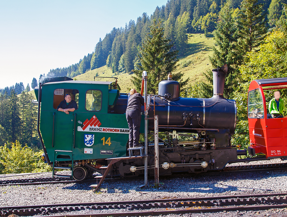 
Die BRB 14 (Gemeinde Brienz) eine Heizöl befeuerte H 2/3 Zahnrad-Dampflok, am 24.09.2016 beim Wasserfassen auf der Mittelstation Planalp (1.341 m ü. M.). 

Bei solch einer modernen Dampflokomotive (befeuert mit Heizöl), entfällt durch die Befeuerungsart der zweite Mann auf der Maschine, der Heizer. Jedoch muss auf der Steilstrecke, auch beim Halt, immer ein Mann auf dem Fahrzeugstand sein, so muss hier die Zugbegleiterin das Wasser nach füllen. 

Die H 2/3 Baujahr 1996 (3. Generation) wurde unter der Fabrik-Nr. 5689 bei der Schweizerische Lokomotiv- und Maschinenfabrik, Winterthur (heute DLM AG) gebaut. 