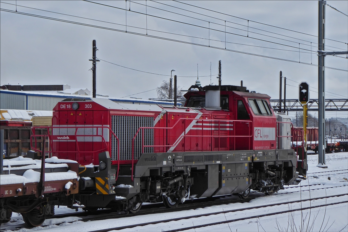 Die CFL Cargo Diesellok DE 18-303 (92 82 4185 303 – 7) steht mit einem Gterzug auf einem Nebengleis im schneebedeckten Bahnhof Belval-Universit. 31.01.2019 (Hans)
Fahrzeugdaten: 
Hersteller: Vossloh; 
Typ: DE 18; 
Baunr. 5502182; 
Bauart: Bo’Bo‘-de; 
Baujahr  2017; 
Spurweite: 1435 mm; 
wurde am 14.12.2017 an die CFL Cargo geliefert.
