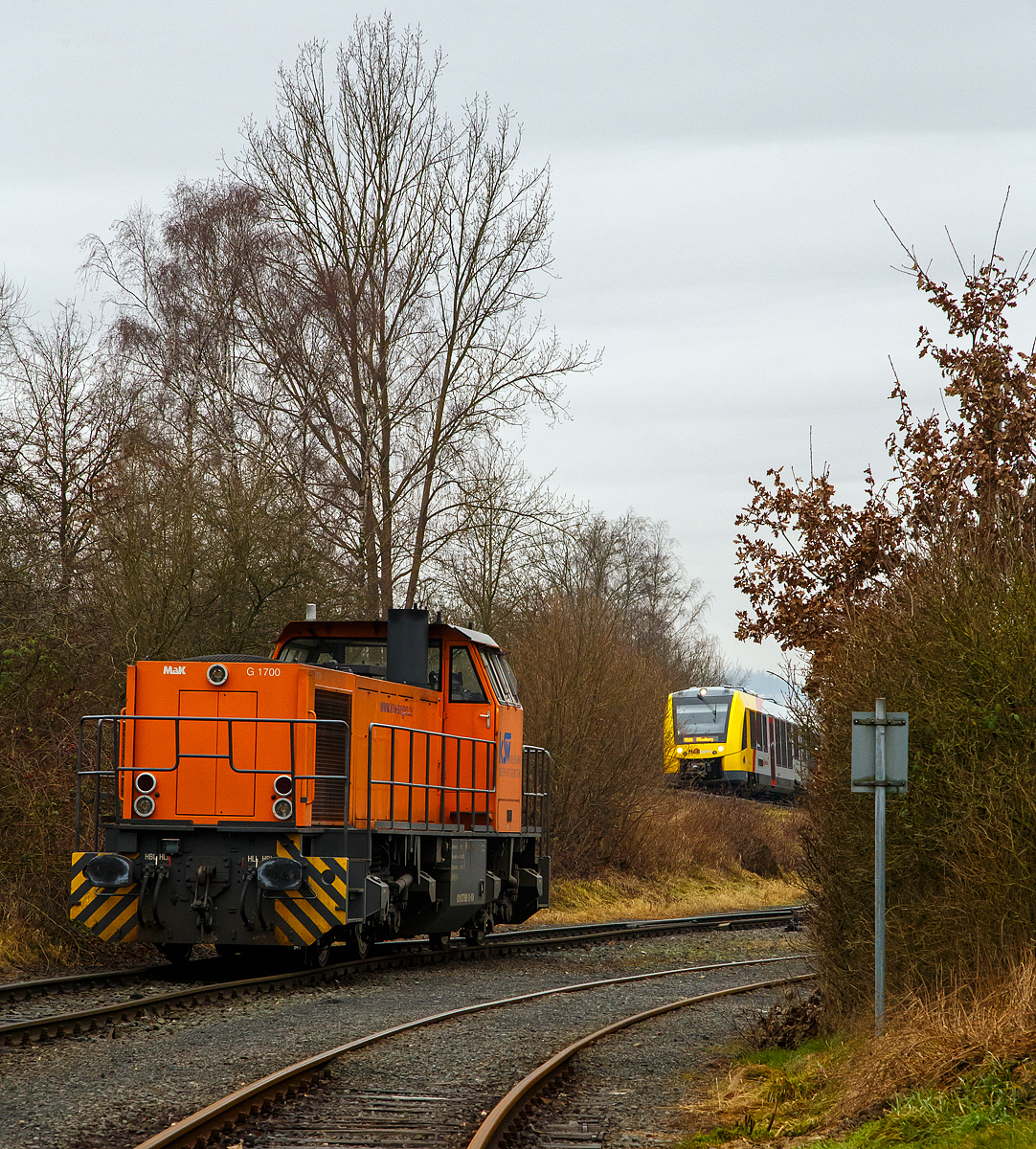 Die KSW 42 (92 80 1277 902-3 D-KSW), eine Vossloh MaK G 1700 BB der KSW (Kreisbahn Siegen-Wittgenstein) steht am 12.01.2022 in Herdorf beim Lokschuppen (nicht im Bild) der KSW (Betriebsstätte Freien Grunder Eisenbahn). Während oben auf der Hellertalbahn (KBS 462 – DB Bahnstrecke Betzdorf-Haiger) der VT 507 (95 80 1648 107-8 D-HEB / 95 80 1648 607-7 D-HEB) der HLB (Hessische Landesbahn GmbH), ein Alstom Coradia LINT 41 der neuen Generation, als RB 96  Hellertalbahn  (Betzdorf - Herdorf - Neunkirchen - Haiger – Dillenburg), von Herdorf weiter in Richtung Neunkirchen bzw. Haiger fährt.