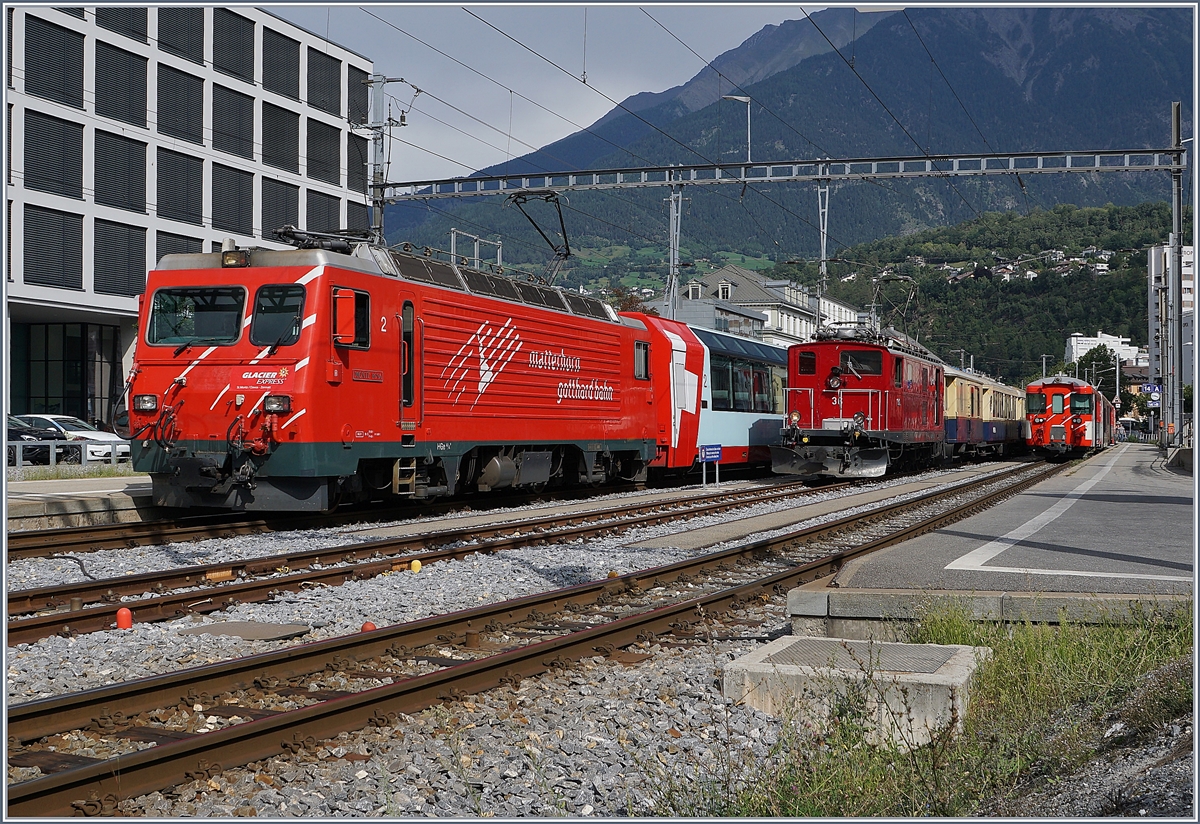 Die MGB HGe 4/4 II  Monte Rosa  verlässt mit dem Glacier Express den Bahnhof von Brig; im Hintergrund steht die die FO HGe 4/4 36 (Baujahr 1948) mit dem  Glacier Pullman Express . 

31. August 2019