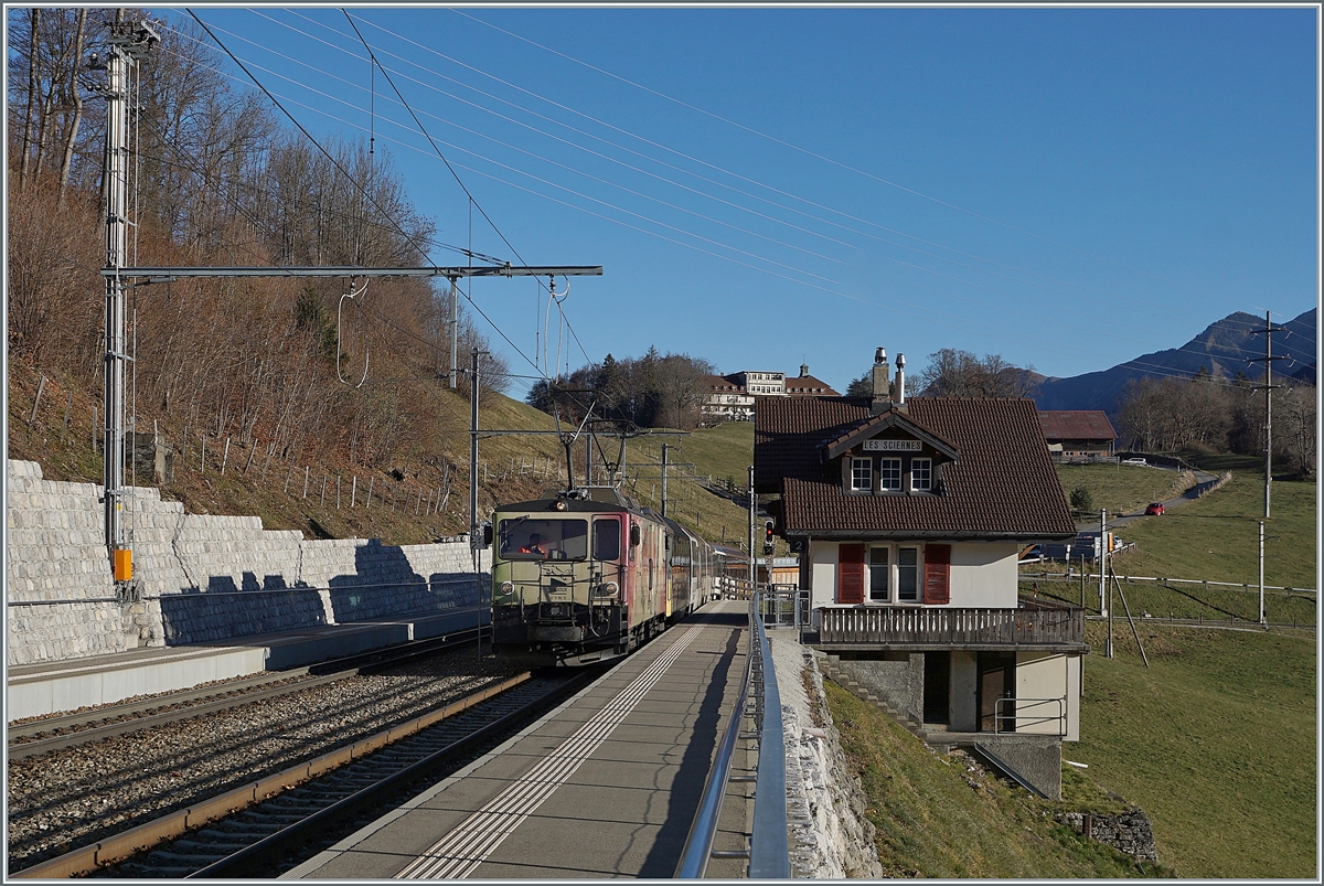 Die MOB GDe 4/4 6006  Aigle les Murailles  ist mit ihrem MOB GoldenPass Panoramic bestehend aus dem Bs 222, Bs 234, Bs 233 und BDs 224 (wobei letztere entgegen der Bezeichnung über 1.Klasse Sitze verfügt) auf dem Weg von Zweisimmen nach Montreux und dabei auf der Durchfahrt in Les Sciernes.

26. Nov. 2020