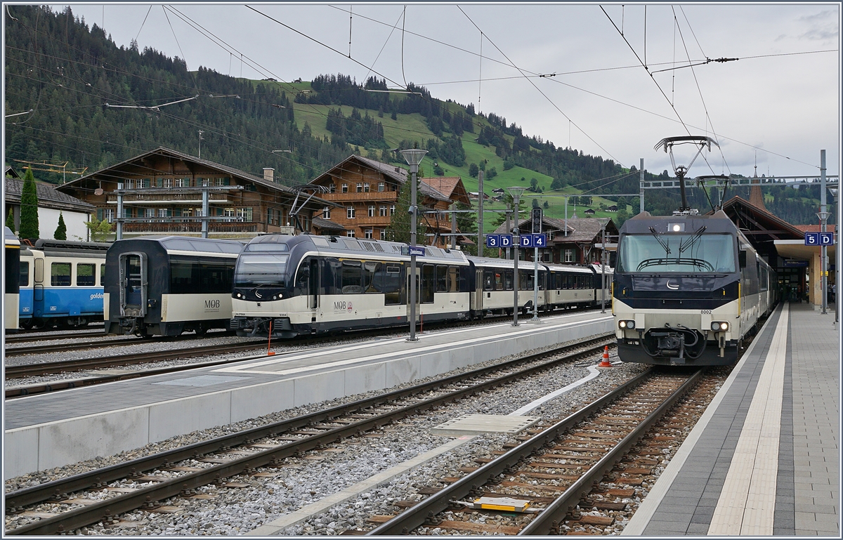 Die MOB Ge 4/4 8002 steht mit ihrem Panoramic Express in Zweisimmen zur Abfahrt nach Montreux bereit während links im Bild ein MOB Alpina Zug auf neuen Aufgaben wartet und ganz links im Bild zeigt sich ein (sehr kleiner Tiel) eines ABDe 8/8 zwischen den Wagen. 

19. August 2020