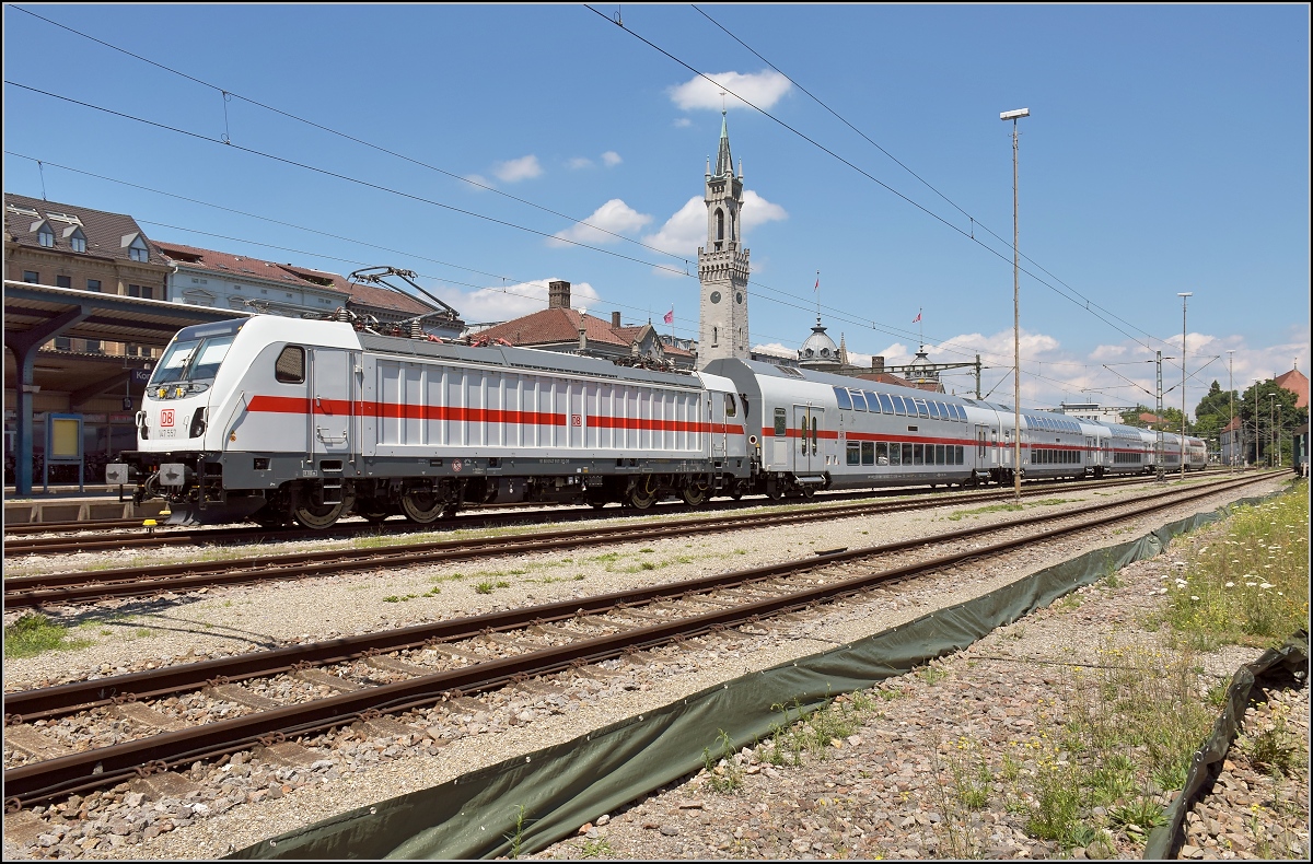 Die neue, leider neigetechniklose Gäubahn wagt sich erstmals auf die Strecke. 147 557 mit dem schweizgängigen Dostopark kommt am alternativen Streckenast in Konstanz an. Vor dem Bahnhofstürmchen von Konstanz einmal südliches Flair schnuppern. Juli 2018.