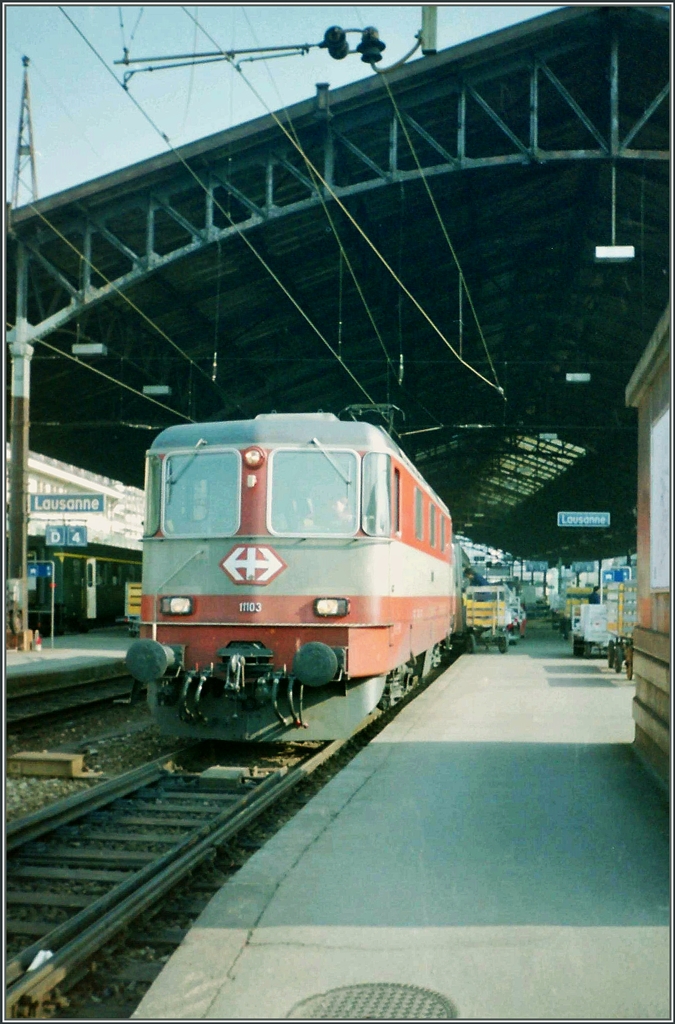 Die Swiss Express Re 4/4 II 11103 mit einem IR (aus EW III) Luzern Langnau - Bern Lauanne - Genève beim Halt in Lausanne. 
März 1994 