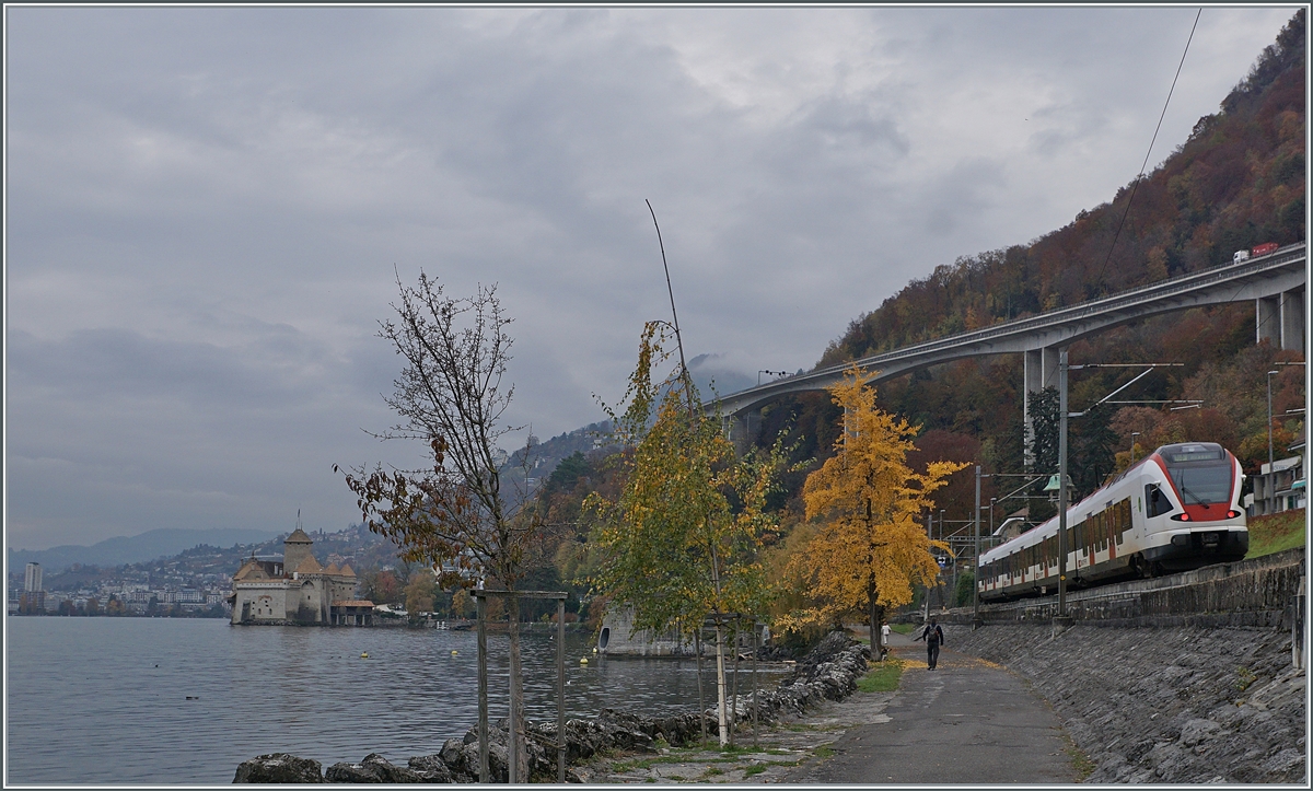 Ein SBB Flirt ist an einem düsteren Herbsttag auf der Fahrt in Richtung Lausanne und wird bald am Schloss von Chillon vorbeifahren. 

3. Nov. 2020