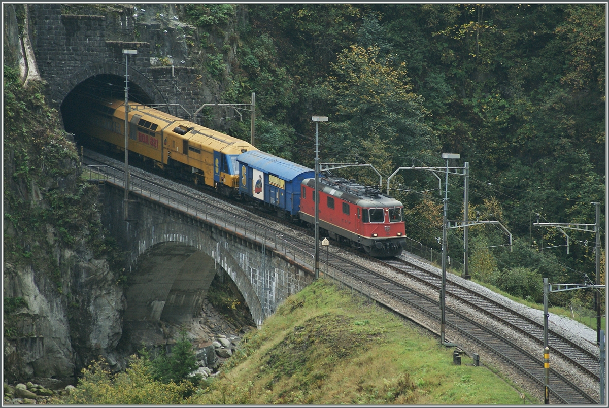 Eine Re 4/4 II mit  gelben Anhang  verlässt den Wattinger Kehertunnel bei Wassen.
10. Okt. 2014