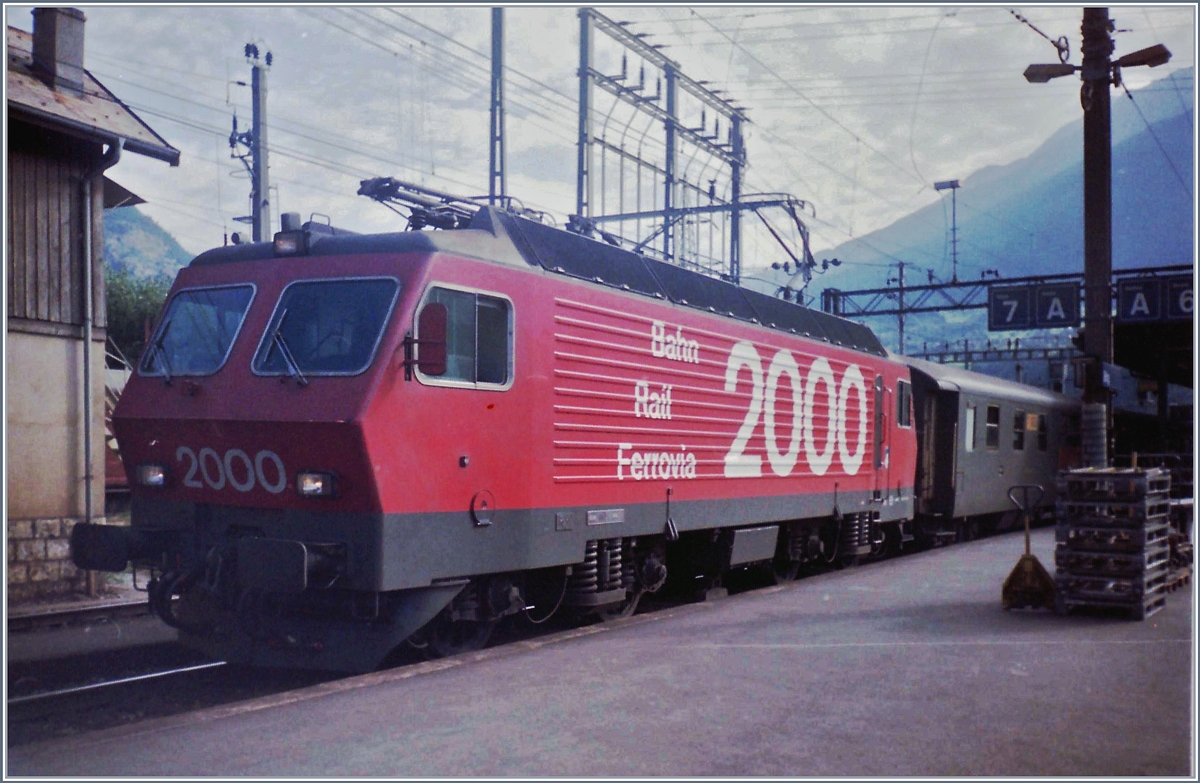 Eine SBB Re 4/4 IV mit einem Schnellzug Richtung Bern (auf dem Bild ist davon nur ein verdeckter Postwagen zu sehen) in Brig.
März 1983