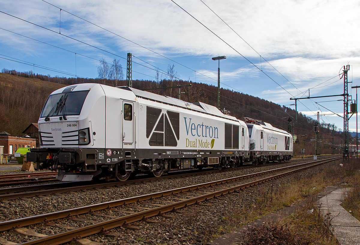 Hat da jemand vielleicht die Stromrechnung nicht bezahlt.... 
Denn die beiden Siemens Vectron Dual Mode Loks, 248 004 (90 80 2248 004-4 D-SIEAG) und die 248 003 (90 80 2248 003-6 D-SIEAG) der Siemens Mobility GmbH, fahren am 20.03.2021, mit abgesenkten Stromabnehmern als Lokzug, obwohl die Strecke elektrifiziert ist, über die Siegstrecke (KBS 460) durch Niederschelden in Richtung Siegen. 

Beide Vectron DM wurden 2020 von Siemens Mobility GmbH in München-Allach gebaut, die 248 004 unter der Fabriknummer 22927 und die 248 003 unter der Fabriknummer 22926. Am 29. Oktober 2020 wurde vom Eisenbahn-Bundesamt (EBA) die Zulassung für den Betrieb der Siemens Vectron Dual Mode Loks in Deutschland erteilt. Einige Unternehmen haben sie auch schon bestellt. Auch die DB Cargo bestellte 100 Zweikraftlokomotiven im September 2020 der auf Basis der Baureihe 248, mit einer Option über weitere 300 Loks. Die Auslieferung startet ab 2023. Die DB Loks sind aber stark modifiziert, so soll bei ihnen die Achslast maximal 21 t betragen (statt 22,5 t).

Hybrid muss nicht immer Akkunutzung heißen. Siemens neue Vectron hat neben der Elektrofähigkeit unter Fahrdraht auch einen Dieselmotor.

Der Vectron Dual Mode vereint die Vorteile einer vollwertigen Diesellokomotive mit denen von elektrischen Lokomotiven. Dank des leistungsstarken Dieselantriebs sowie der Ausstattung für die Nutzung der Fahrleitung kann man jederzeit flexibel auf die Traktionsanforderungen reagieren. So bleibt man immer in Bewegung, egal ob mit oder ohne Fahrdraht. Wo ein Fahrdraht ist, sollte man ihn nutzen. Denn der Betrieb unter Oberleitung ist im Vergleich zum Dieselbetrieb deutlich kosteneffizienter und umweltfreundlicher. Doch weil es in Deutschland noch lange Zeit Strecken geben wird, die nicht vollständig elektrifiziert sind, fahren viele Diesellokomotiven unter Fahrdraht weiter. Das ist aber ökonomisch und ökologisch wenig sinnvoll. Dies ist hier ein Beispiel einer echten Alternative. 

Mit der Vectron Dual Mode ist es möglich Güterzüge aus dem Umland umweltschonend in die Zentren der Ballungsräume zu befördern. Nur so einfach, wie in der Siemens Werbung ist es auch nicht, denn die Lok vier Achsen (Bo’Bo’) und wiegt 90 t, so ergibt sich eine Achslast  von 22,5 t. Nicht elektrifizierte Nebenstrecken haben nicht gerade alle von min. D2 (22,5 t), und können so auch nicht befahren werden. Auch die Leistung der DM im Vergleich zu heutigen Hochleistungselektrolokomotiven ist mit 2.400 kW erheblich geringer. Mit den Dieselstreckenlos kann sie aber mit 2.000 kW sehr gut mithalten, zudem liegt die Anfahrzugskraft bei stattlichen 300 kN.

TECHNISCHE DATEN der Siemens Vectron Dual Mode (BR 248)
Spurweite: 1.435 mm
Achsformel: Bo'Bo'
Länge über Puffer: 19.975 mm
Drehzapfenabstand: 10.800 mm
Achsabstand im Drehgestell: 2.700 mm
Breite: 3.020mm
Höhe:  4.220 mm
Raddurchmesser :  1.100 mm (neu) / 1.020 mm (abgenutzt)
Gewicht:  90 t (bei vollen Vorräten)
Achslast: 22,5 t
Spannungssysteme (bei E-Betrieb): 15 kV, 16,7 Hz
Dieselmotor: MTU 16V 4000 R84 (16-Zylinder-V-Motor)
Dieselmotorleistung an der Kurbelwelle: 2.400 kW
Max. Leistung am Rad: 2.400 kW bei E-Antrieb / 2.000 kW bei D-Antrieb
Höchstgeschwindigkeit:160 km/h
Antriebsart: elektrisch oder dieselelektrisch
Kraftübertragung :Teilabgefederter Antrieb (Ritzelhohlwellenantrieb)
Kraftstoffbehälter Nutzvolumen: 2.600 l
Anfahrzugskraft:  300 kN
Elektrische Bremskraft: 150 kN
Elektrische Bremsleistung (am Rad): E-Betrieb 2.100 kW / Dieselbetrieb 1.700 kW
Doppeltraktion: Über WTB ÖBB mit typgleichen Fahrzeugen sowie Vectron E, Vectron DE und ER20
Zugsicherung: PZB / für ETCS vorbereitet