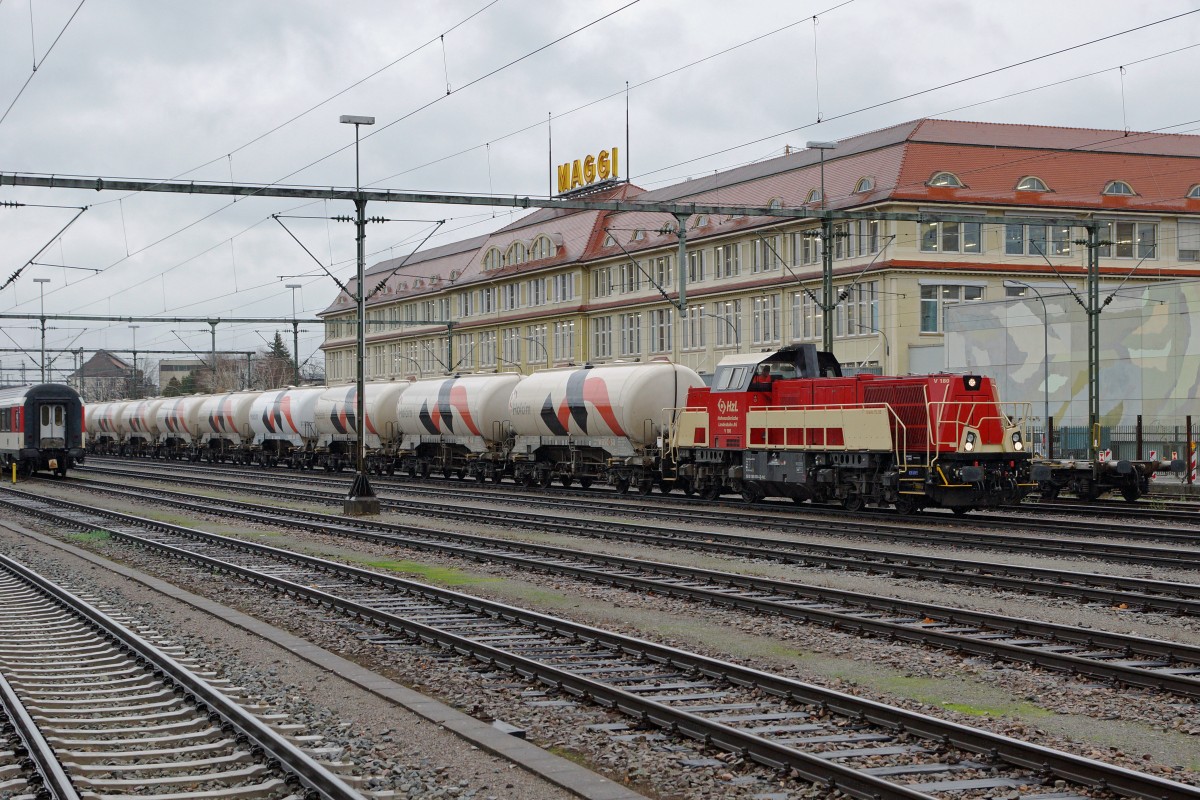 HZL: Fotografieren in Singen am 20. November 2015 trotz starkem Wind und Dauerregen. Die V 180 Gravita 15 L BB mit einem HOLCIM-BLOCKZUG in Singen vor der Kulisse der MAGGI FABRIK, dem Wahrzeichen des Bahnhofs Singen, kurz vor der Abfahrt nach ????
Foto: Walter Ruetsch 
