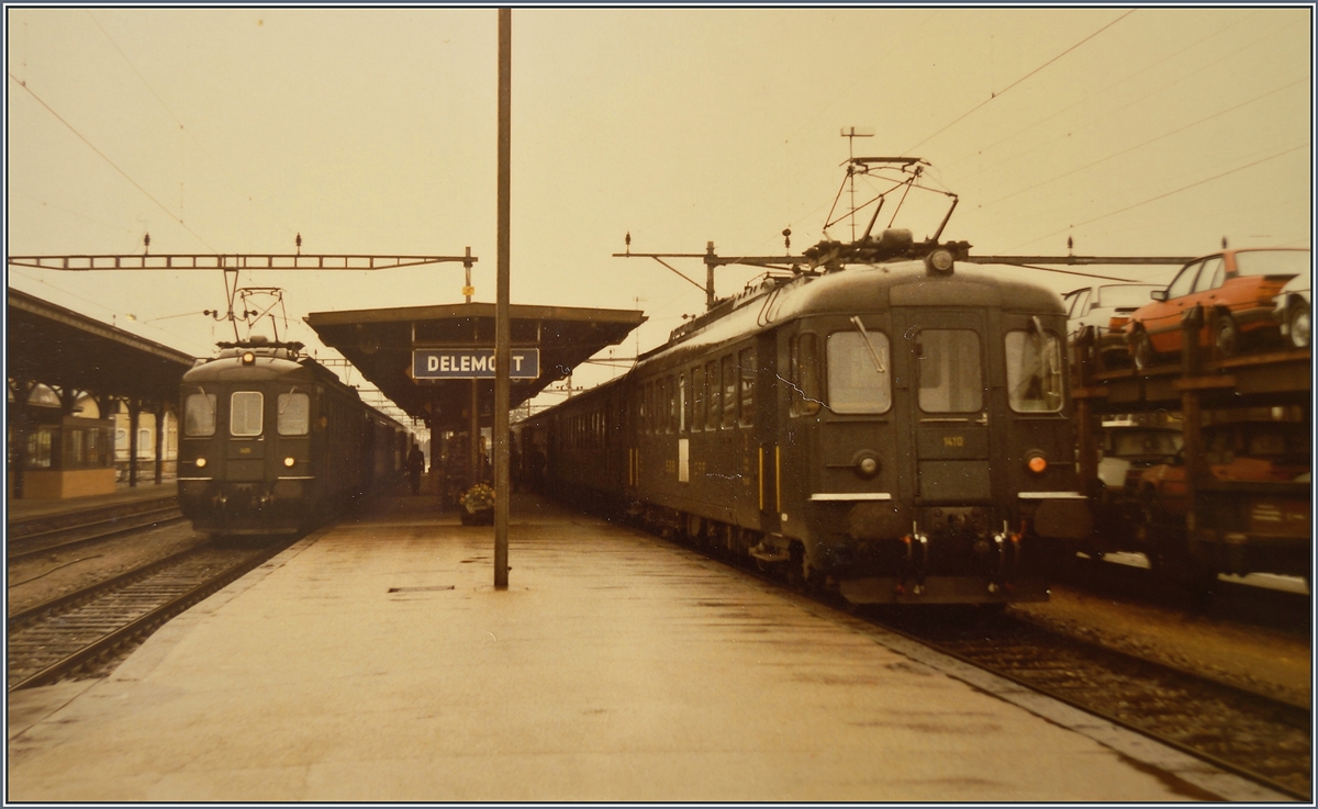 In Delémont warten zwei RBe 4/4 Pendelzüge auf die Abfahrt; interessant auch der Güterzug mit Neuwagen rechts im Bild, welcher wohl vom Peugeot Werk bei Montbéliard via Delle nach Delémont kam. 

16. Sept. 1984