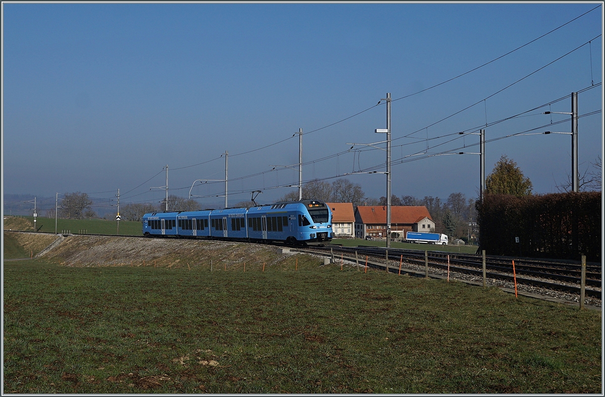 In weiten Kurven windet sich das Trasse der Strecken von Romont nach Vuisternens-devant- Romont, um die gut achzig Höhenmeter zu überwinden. Der im sehr gefälligen Werbeanstrich der  Groupe Grisoni  gehaltene TPF RABe 527 198 hat die Steigung fast geschafft und erreicht in Kürze den Bahnhof Vuisternas-devant-Romont, welcher jedoch wie alle Station zwischen Romont und Bulle nur noch dienstlichen Zwecken dienen.

1. März 2021