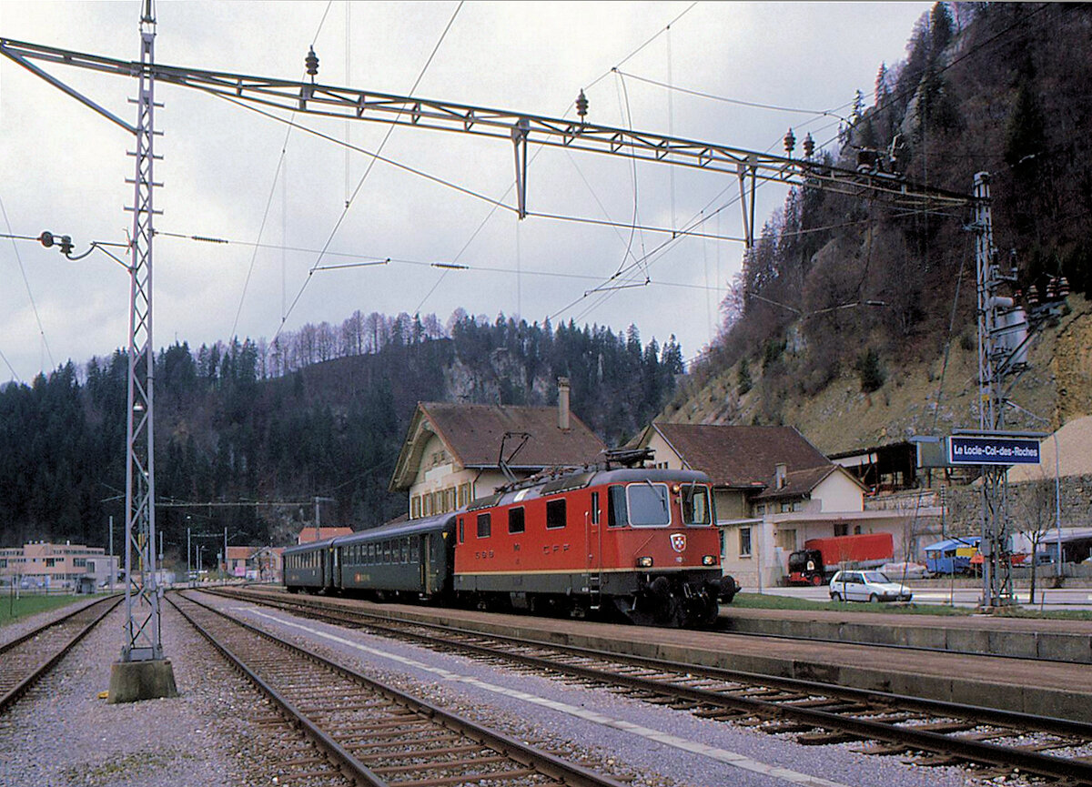 Le Locle - Le Locle-Col-des-Roches: Heute fahren keine planmässigen SBB-Züge mehr zum Talboden nach Col-des-Roches hinunter. Bloss einige ganz wenige SNCF-Triebwagen Richtung Morteau und Besançon kommen hier vorbei, und auch das jetzt nicht mehr (Streckensperrung 1.März - 31.Oktober 2021). Im Tunnel durch den im Hintergrund sichtbaren Berg liegt die schweizerisch/französische Landesgrenze. Im Bild steht die SBB-Komposition mit Lok 11249 und den beiden Zweitklasswagen 20-34 369 und 20-34 138 in Le Locle Col-des-Roches. 20.April 1995 