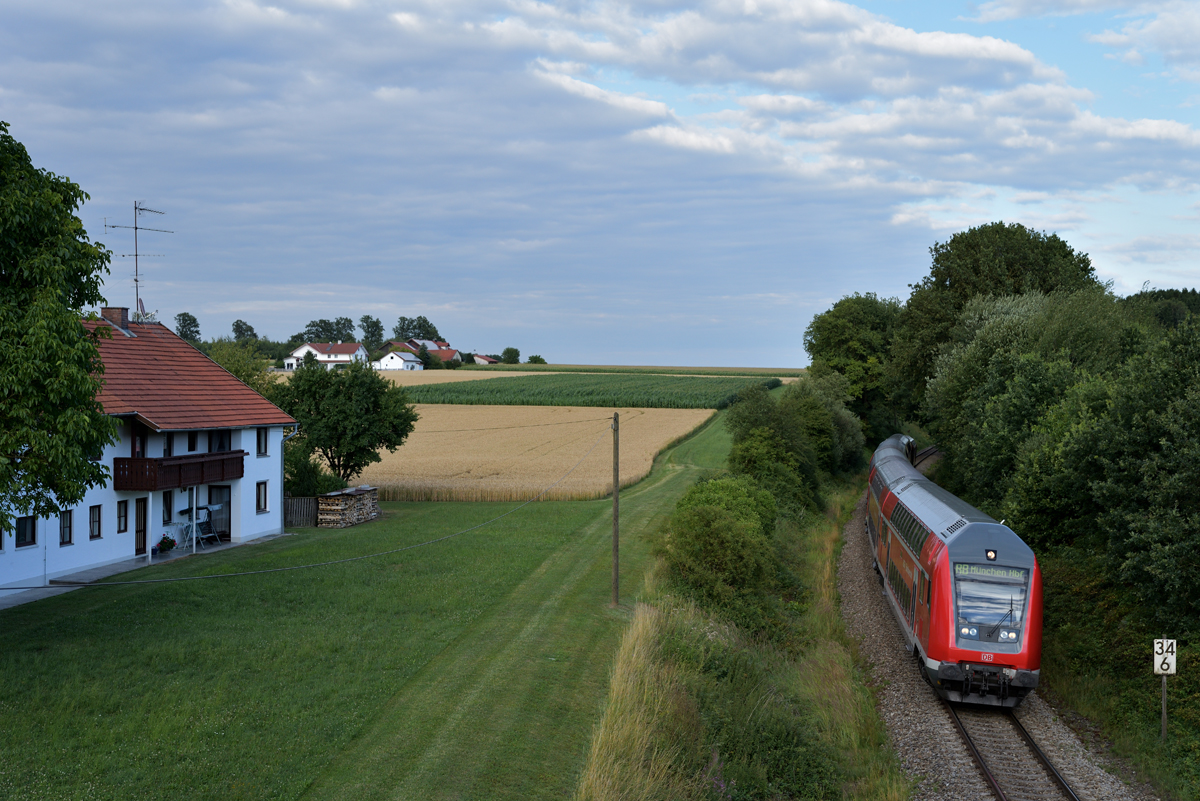 Leider verlor die Sonne am abendlichen 15. Juli 2017 bei Englpolding den Kampf mit einer großen Wolkenfront aus dem Nordwesten, als ein Doppelstockzug von Mühldorf nach München Hbf - geschoben von 245 014-6 - den Kilometer 34.6 passierte.